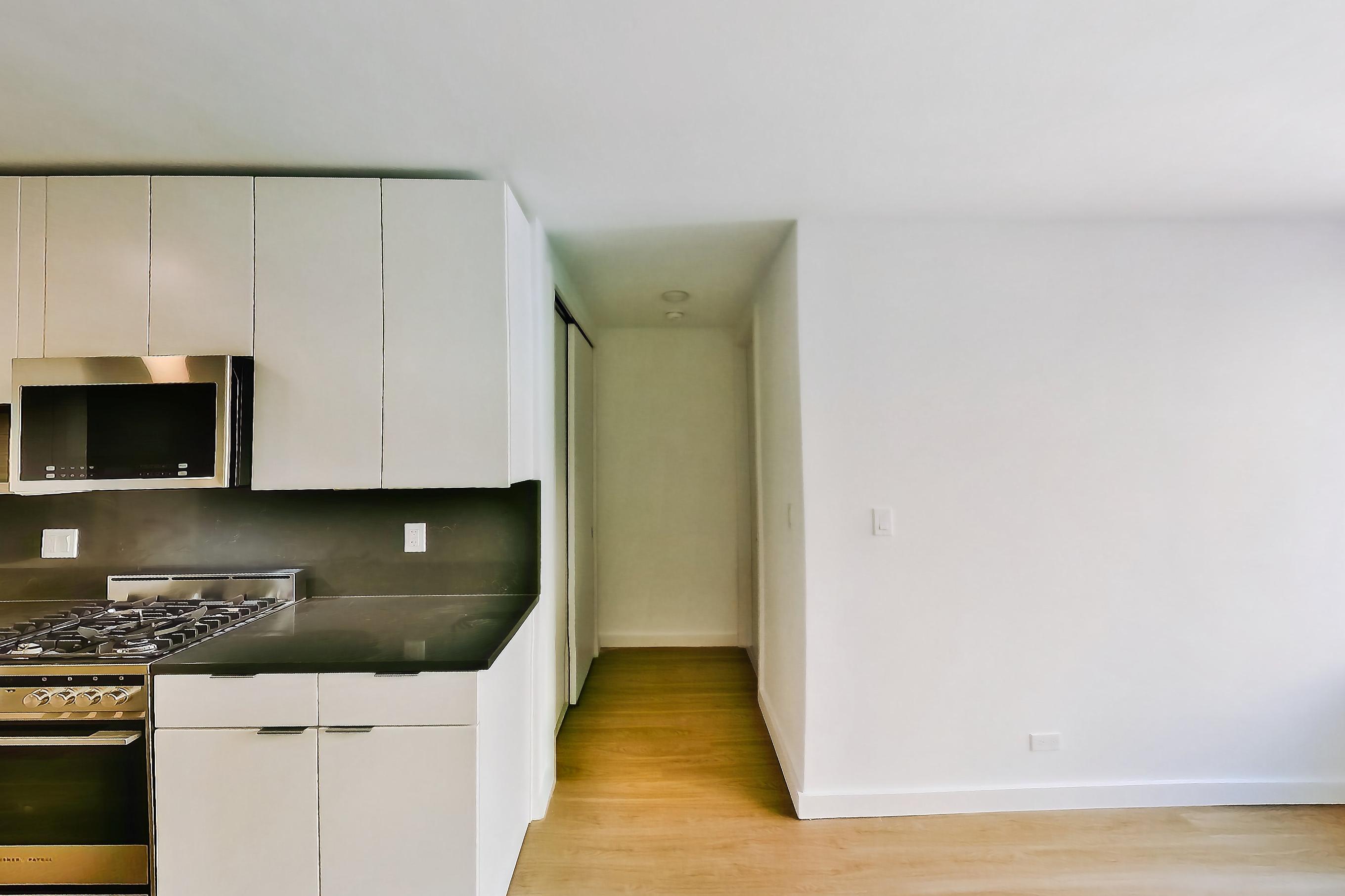Kitchen and living area with light wood-finish flooring, Apartment 07 line studio at Hollingsworth