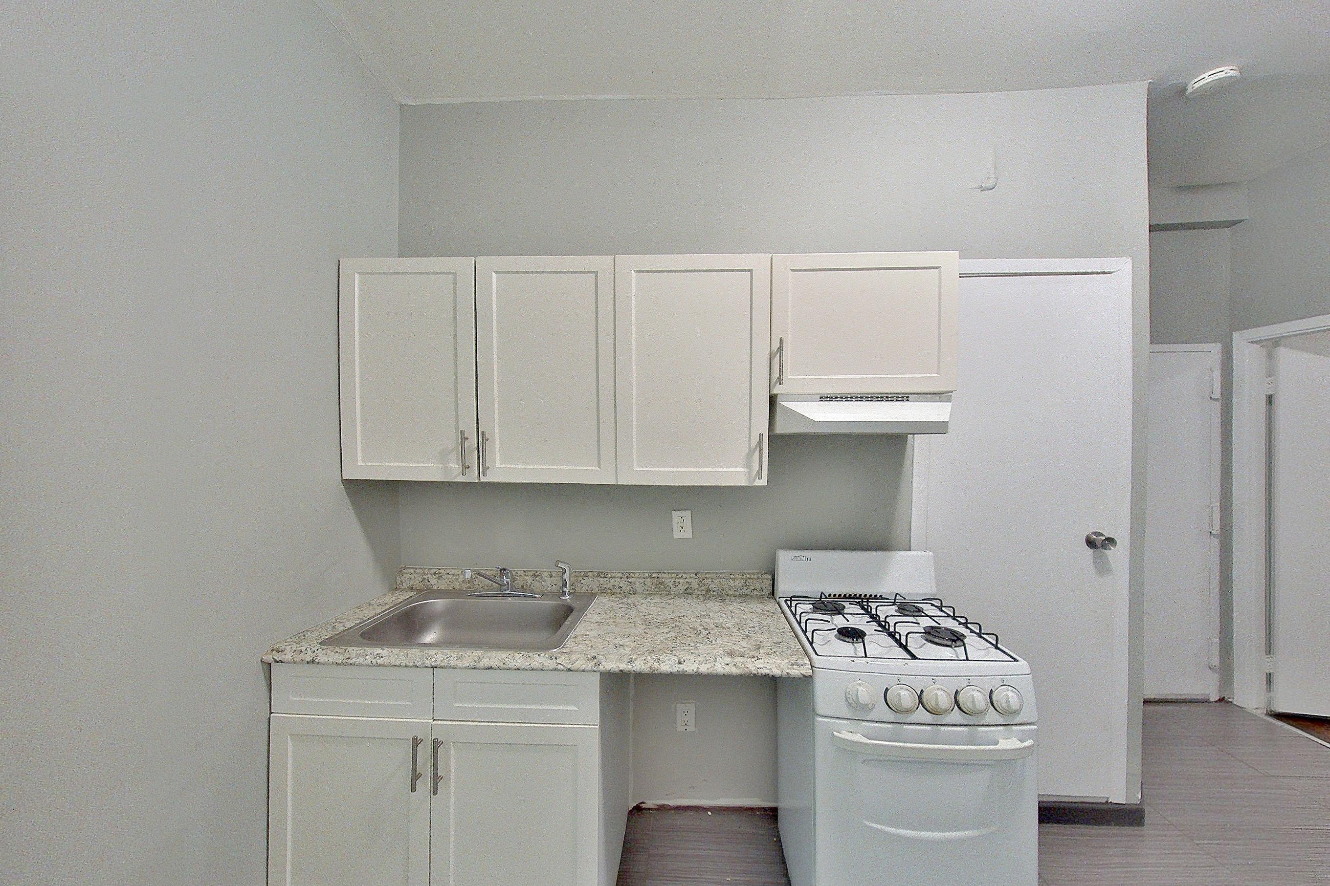 Kitchen with gas range, light stone countertops, light tile flooring, oven/range, radiator heat, and white appliances, Apartment 07 at Metronest Leasing