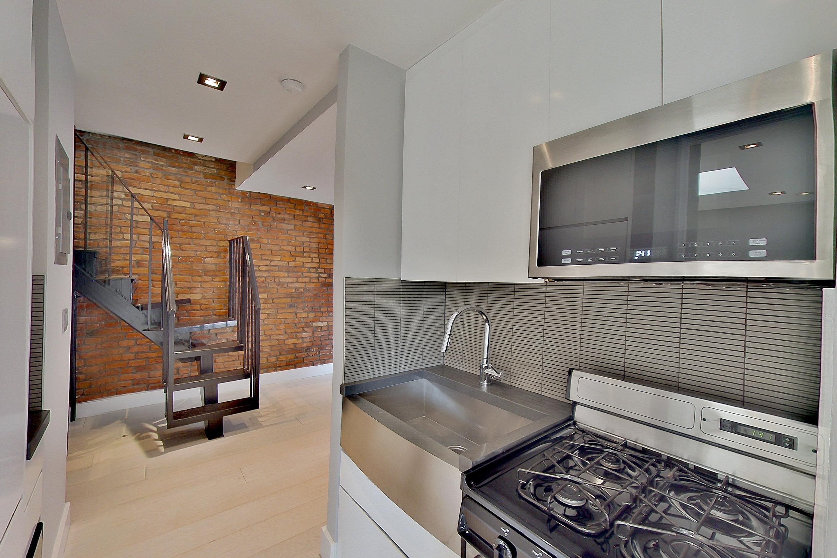 Kitchen with gas range, light wood-finish flooring, oven/range, radiator heat, and stainless steel appliances, Apartment 4 E at Centennial Properties