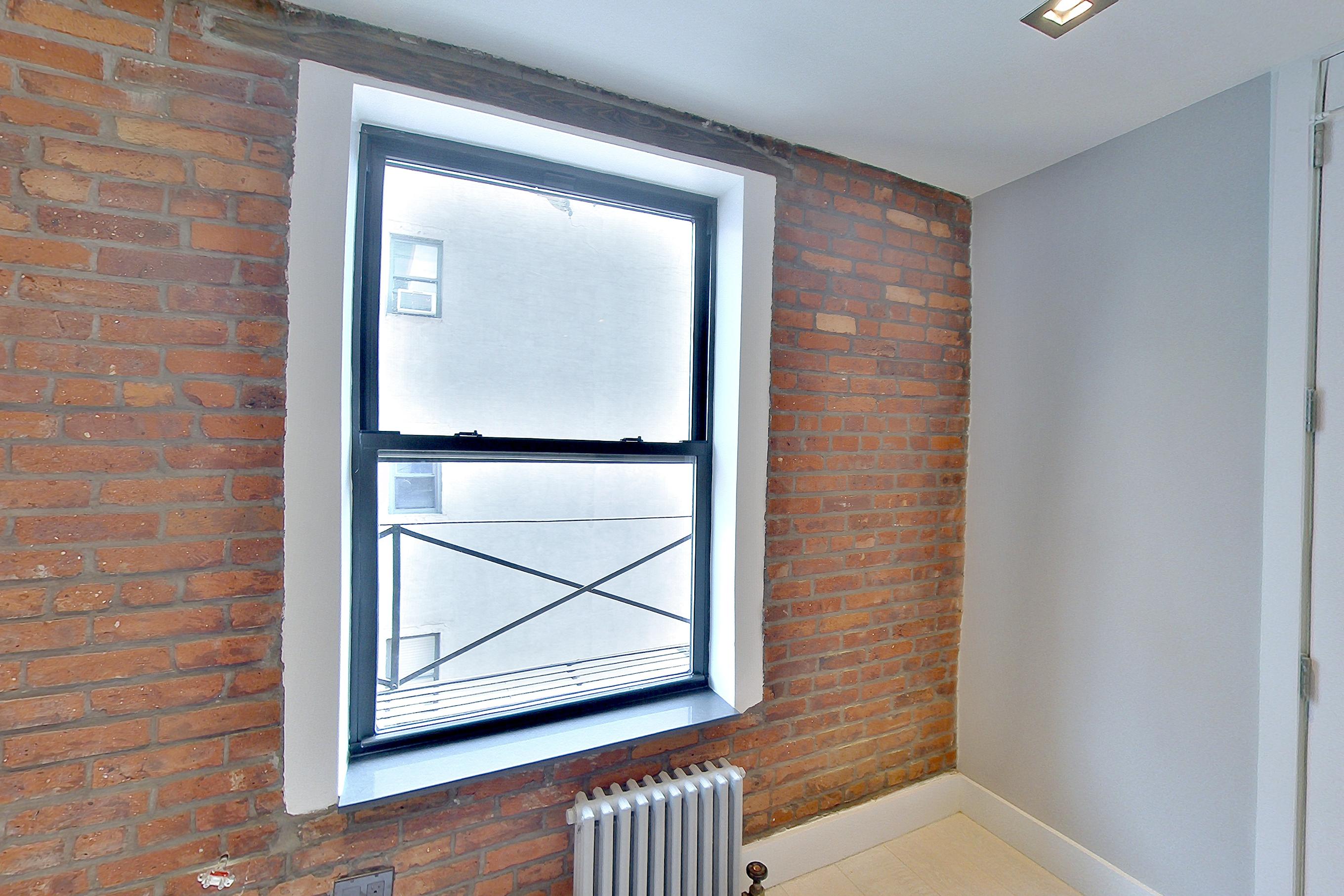 Living room with light wood-finish flooring and radiator heat, Apartment 4 E at Centennial Properties