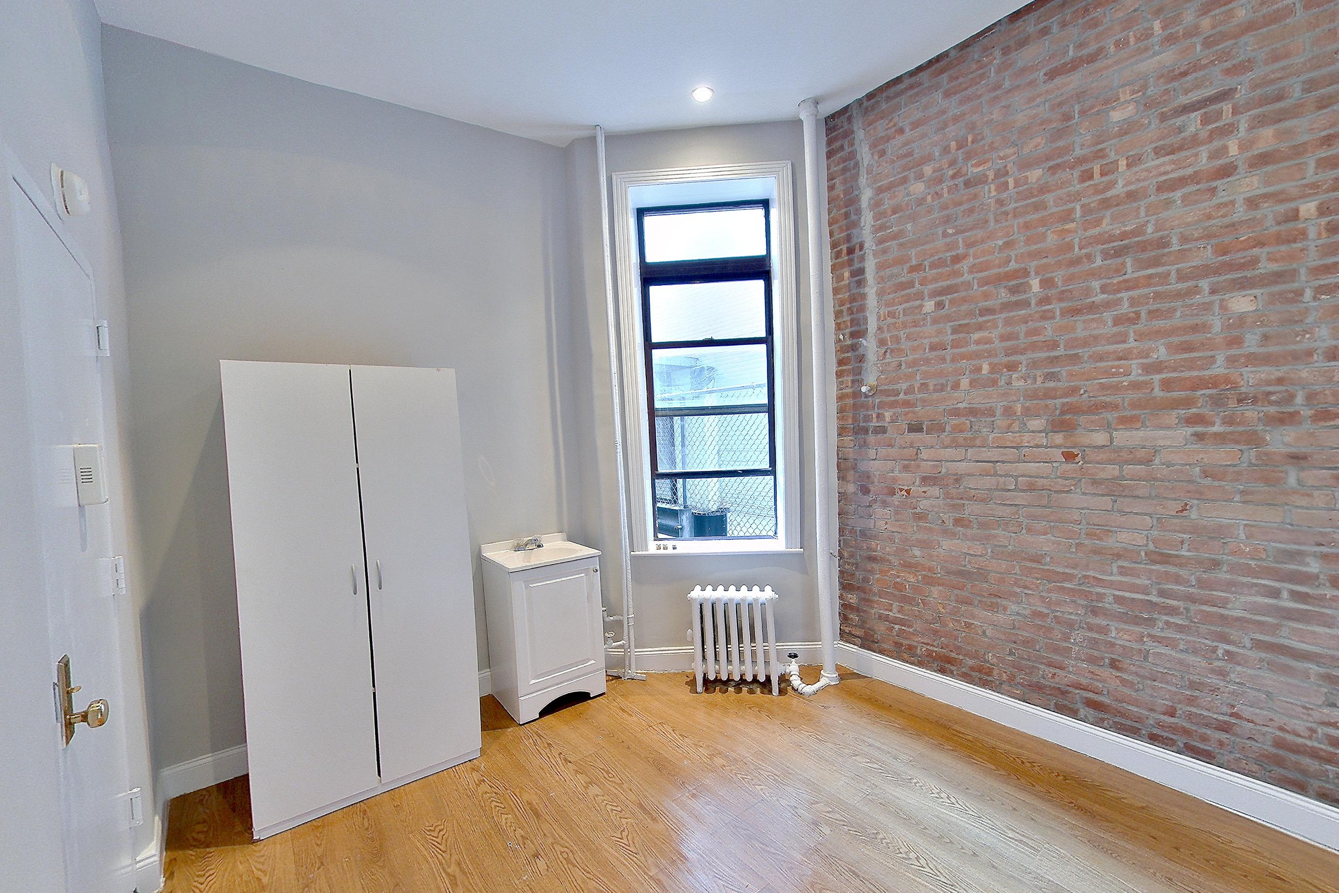 Living space with light wood-finish flooring and radiator heat, Apartment AE at Centennial Properties
