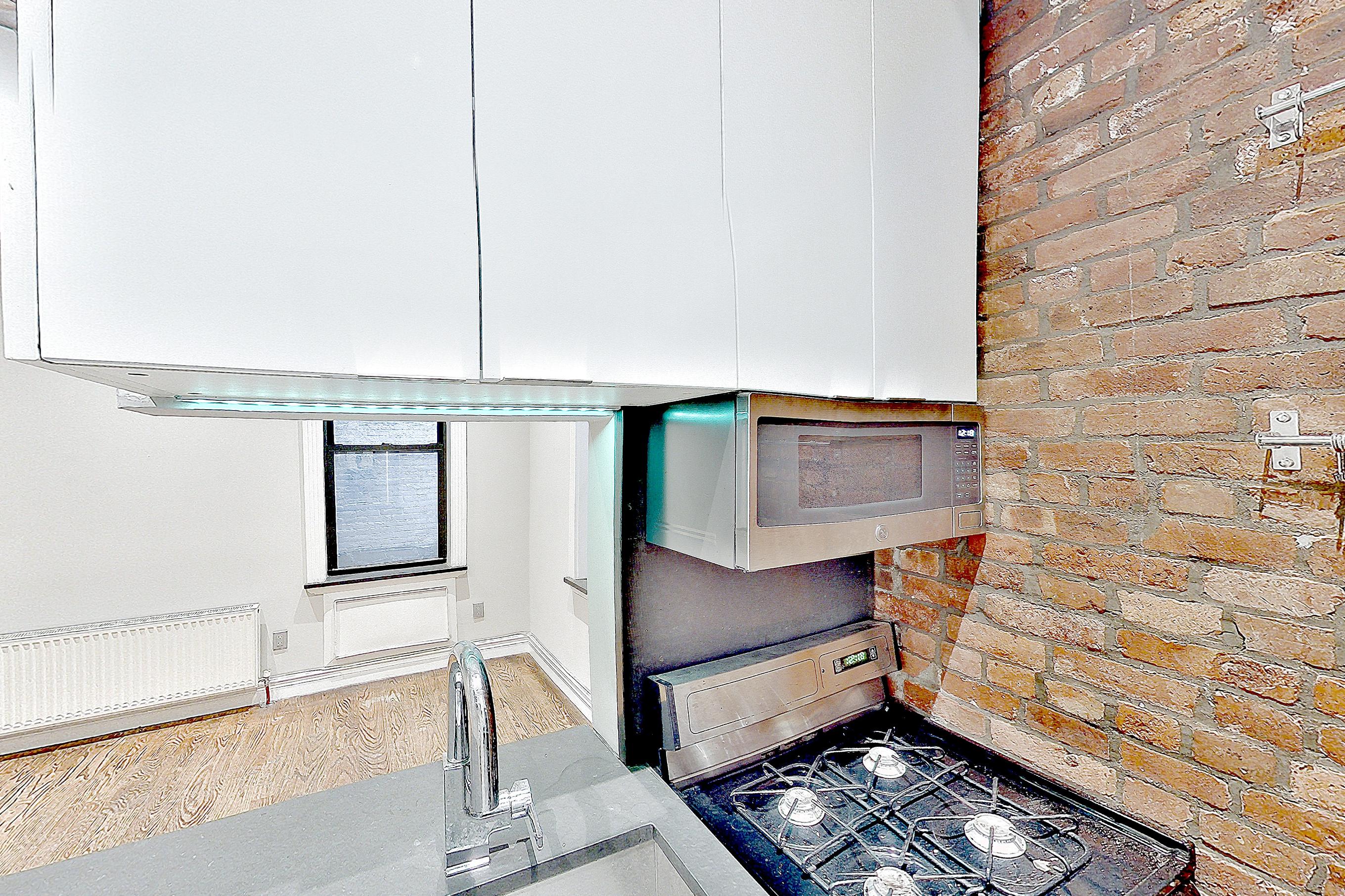 Kitchen with brick-look tile flooring, gas range, oven/range, and stainless steel appliances, Apartment B at Centennial Properties