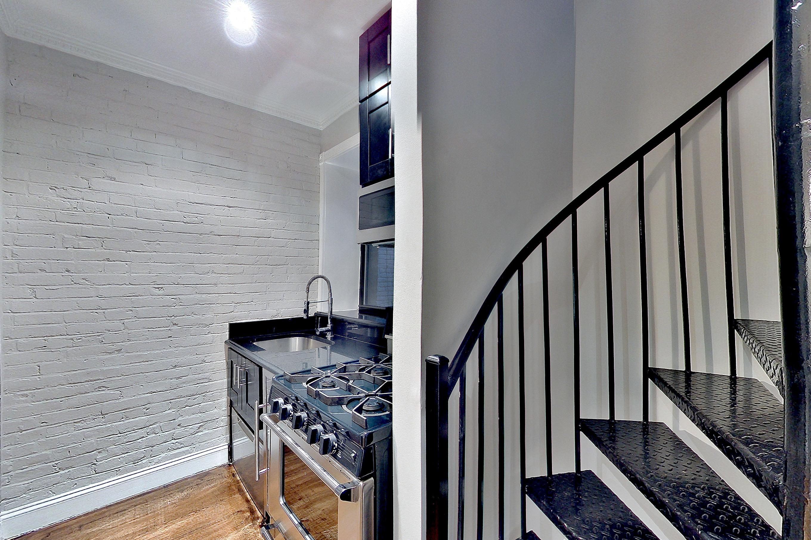 Kitchen with gas range, light wood-finish flooring, oven/range, stainless steel appliances, and wood-finish flooring, Apartment 13E at Centennial Properties