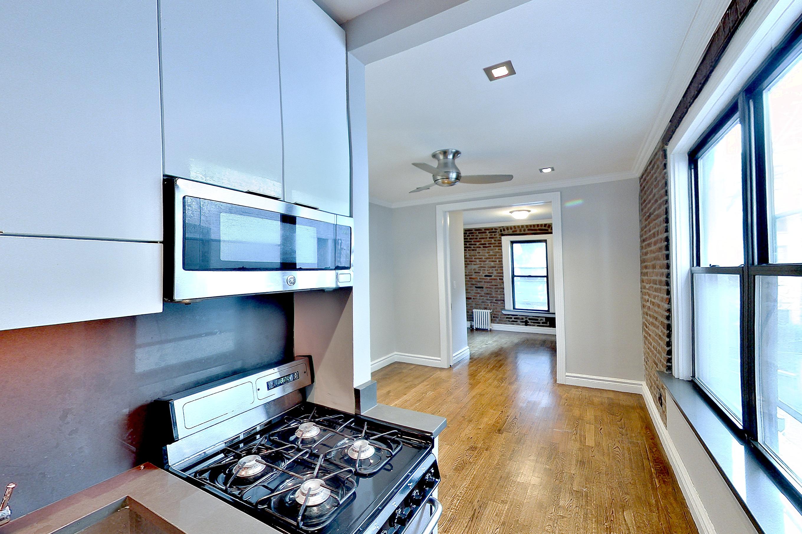 Kitchen with gas range, light wood-finish flooring, oven/range, radiator heat, and stainless steel appliances, Apartment 2F at Centennial Properties