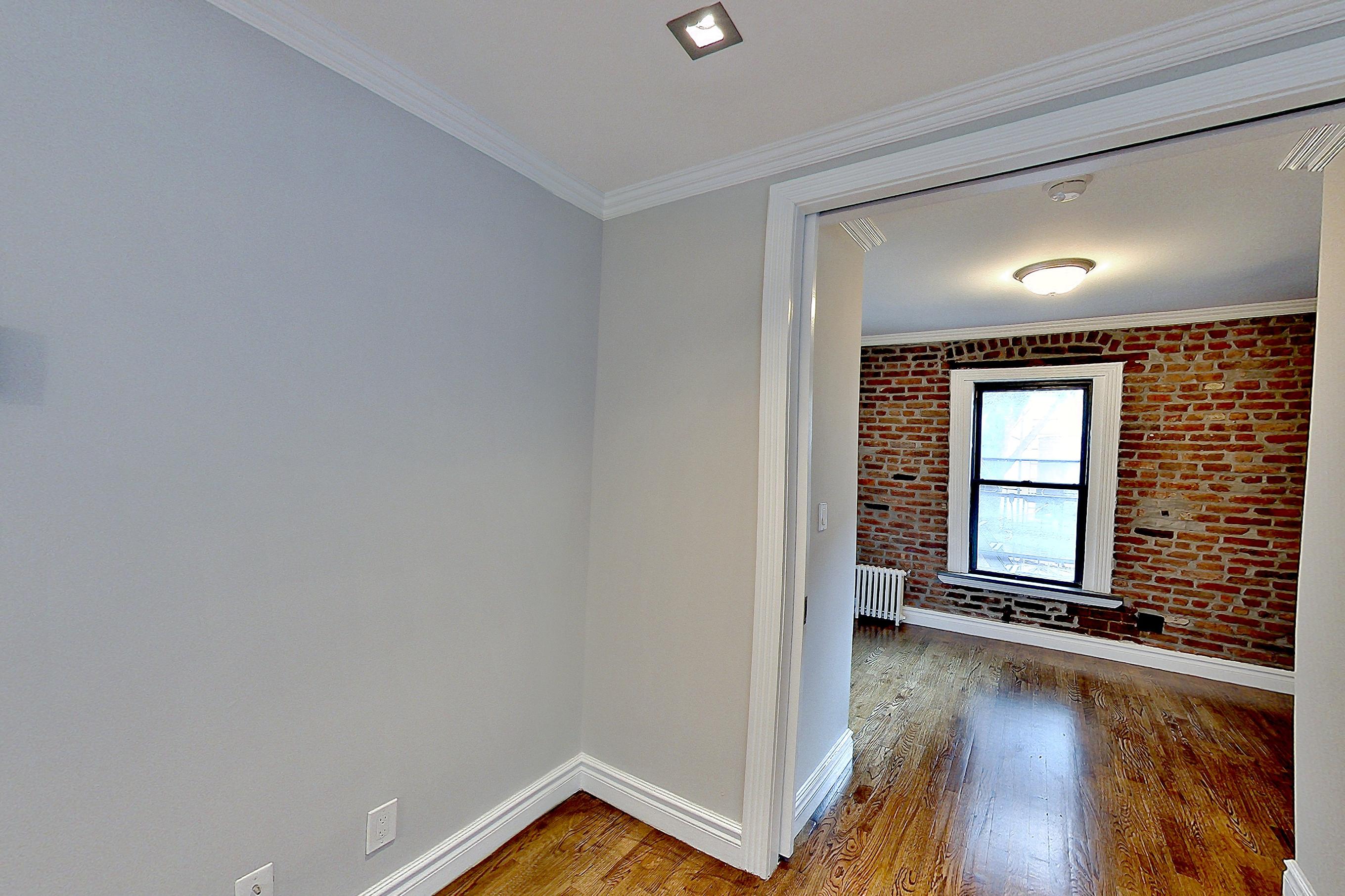 Living room with radiator heat and wood-finish flooring, Apartment 2F at Centennial Properties