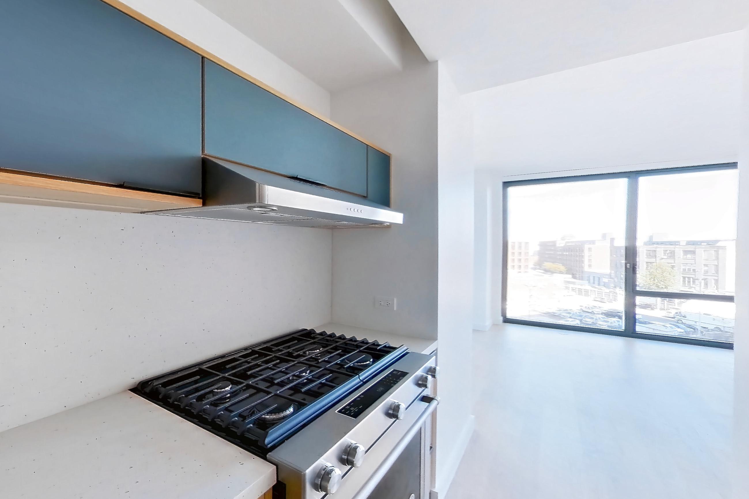 Kitchen with gas range, light wood-finish flooring, oven/range, and stainless steel appliances, Apartment 0-05E at The Bellslip
