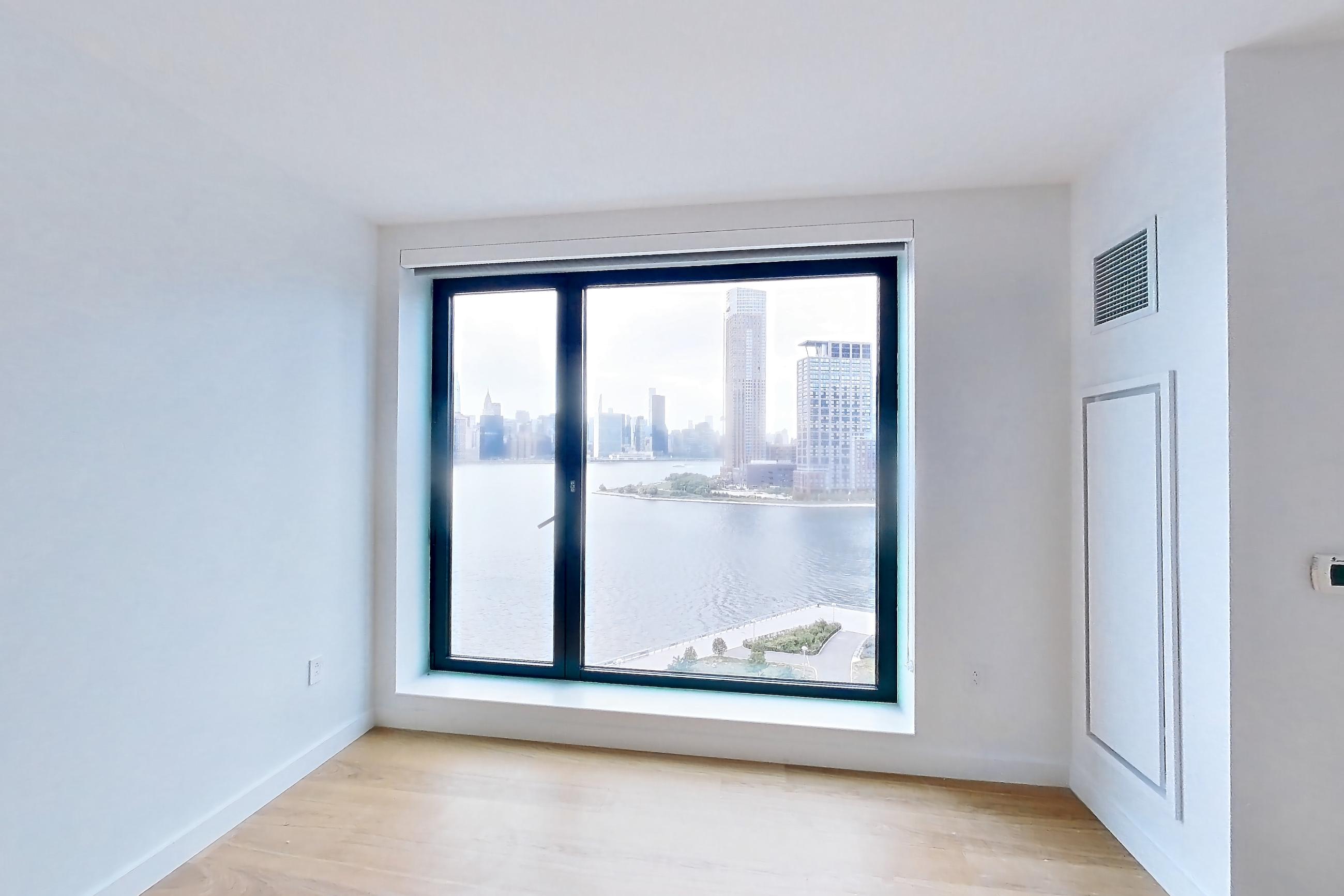 Living room with city view, light wood-finish flooring, and water view, Apartment 1025 at Eagle + West