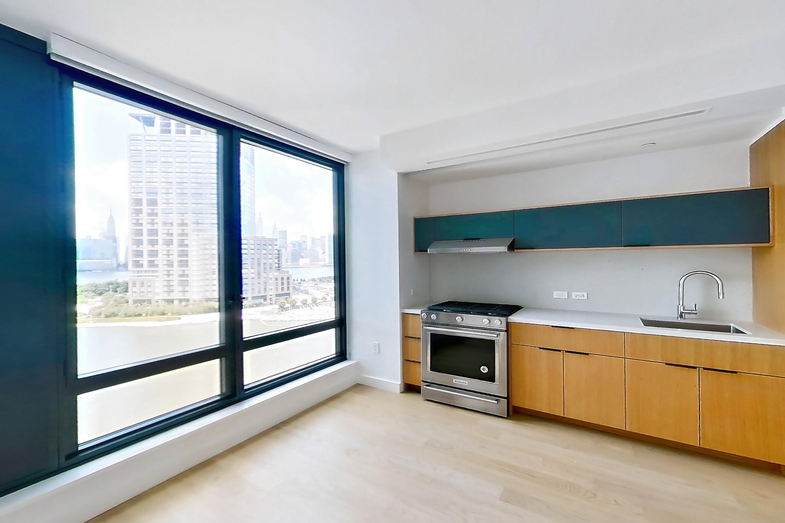 Living room with city view, gas range, light wood-finish flooring, oven/range, and stainless steel appliances, Apartment 0-08H at The Bellslip