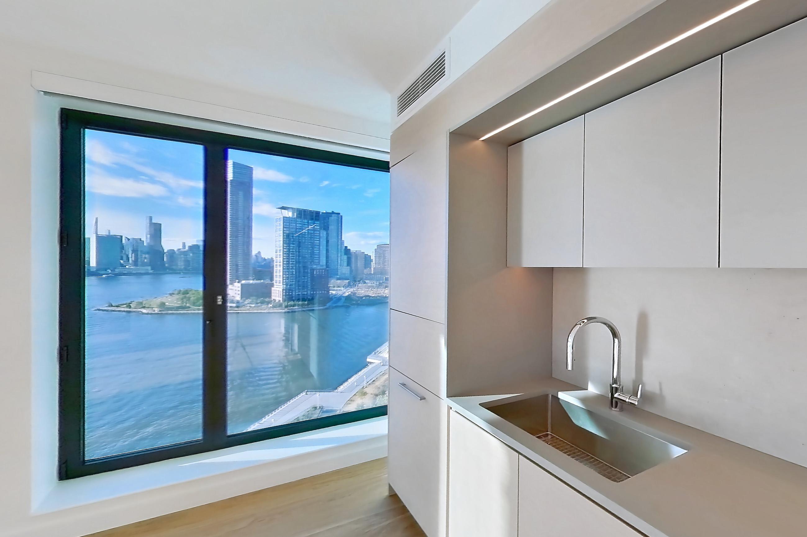 Kitchen with city view, gas range, light wood-finish flooring, oven/range, skyline view, and stainless steel appliances, Apartment 2-1526 at Eagle + West