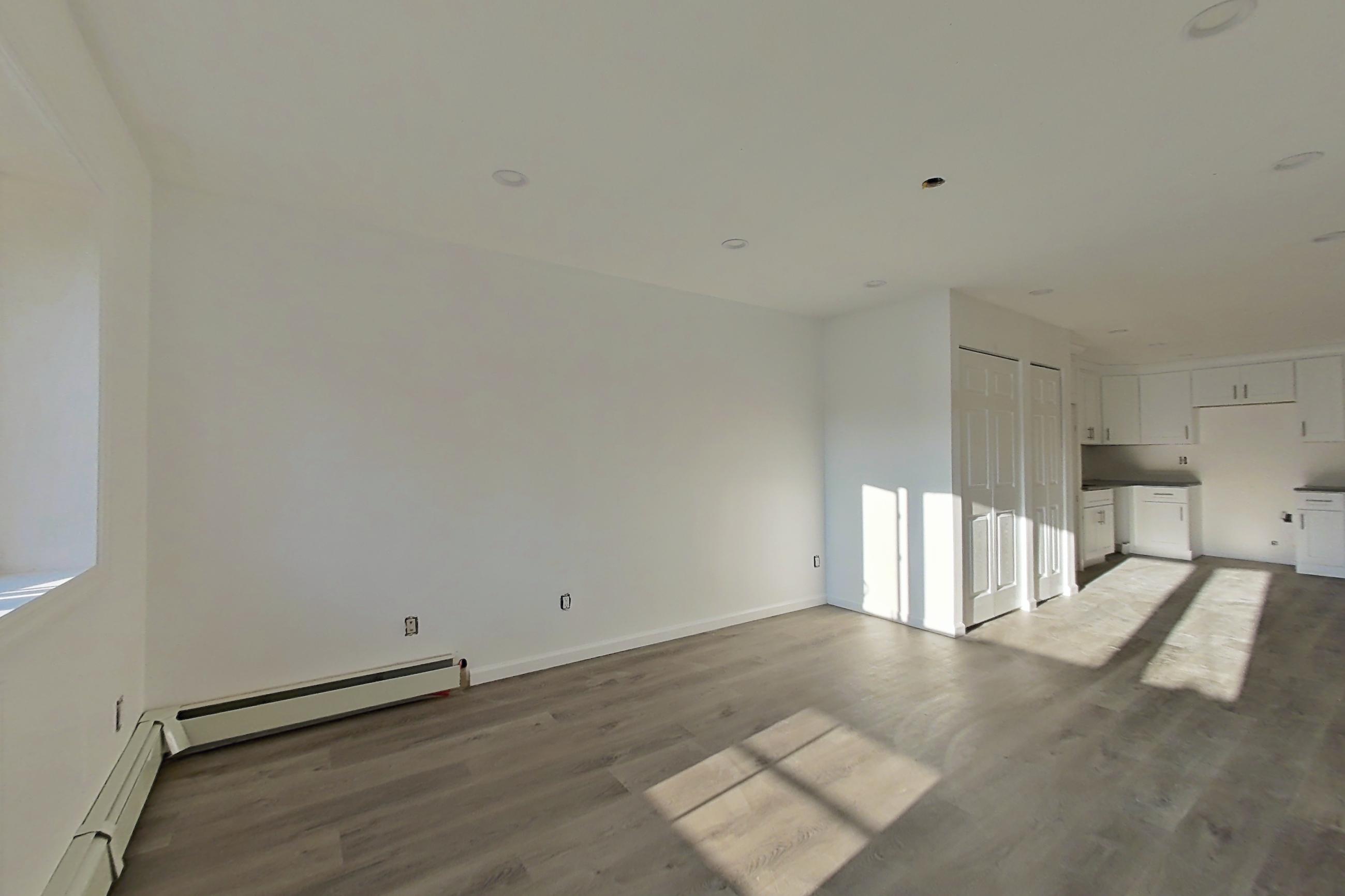 Living room corner 1 with baseboard heating and dark wood-finish flooring, Apartment 03 at Platinum Properties