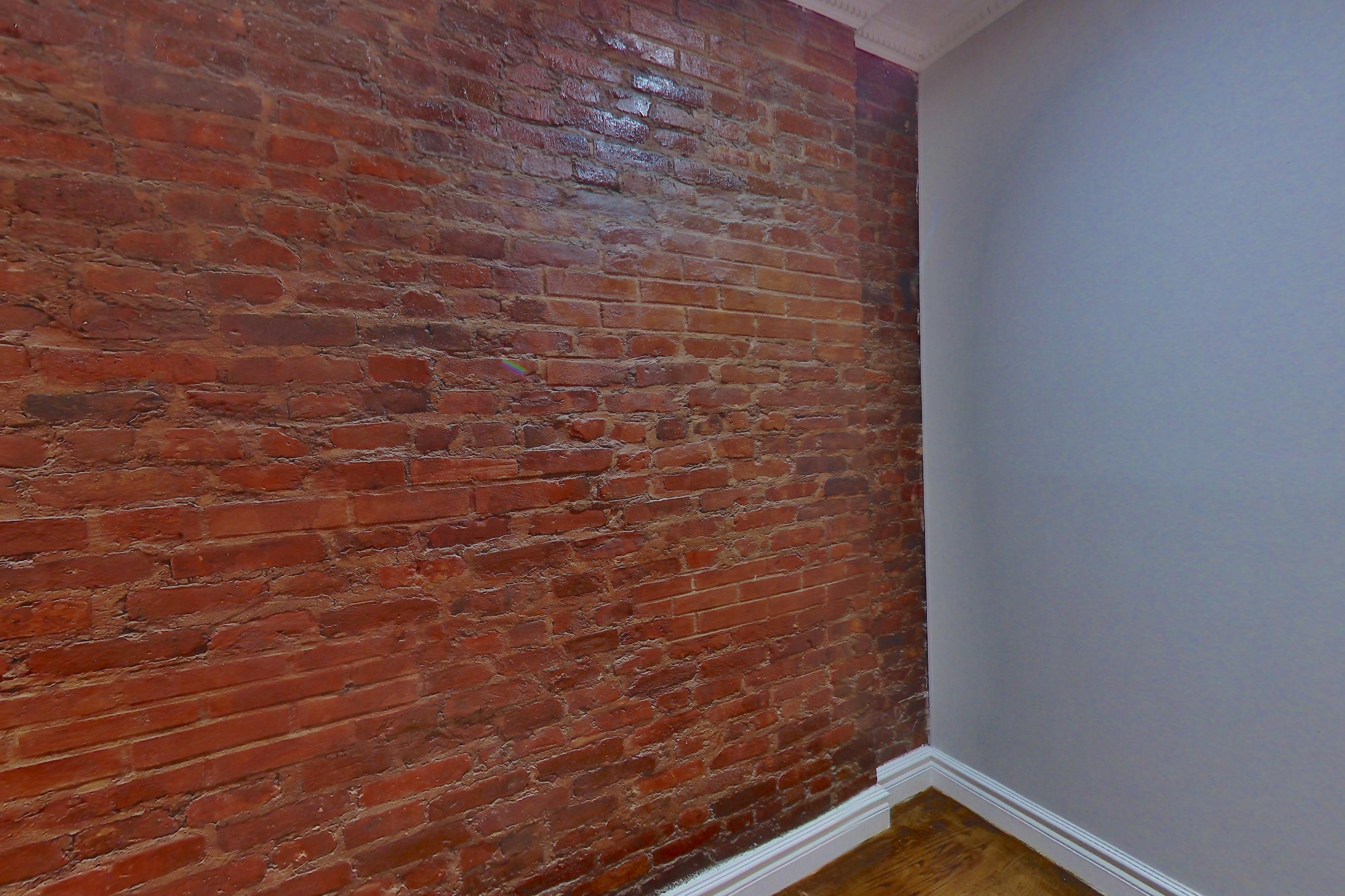 Living room with brick-look tile flooring, Apartment 1B at Centennial Properties