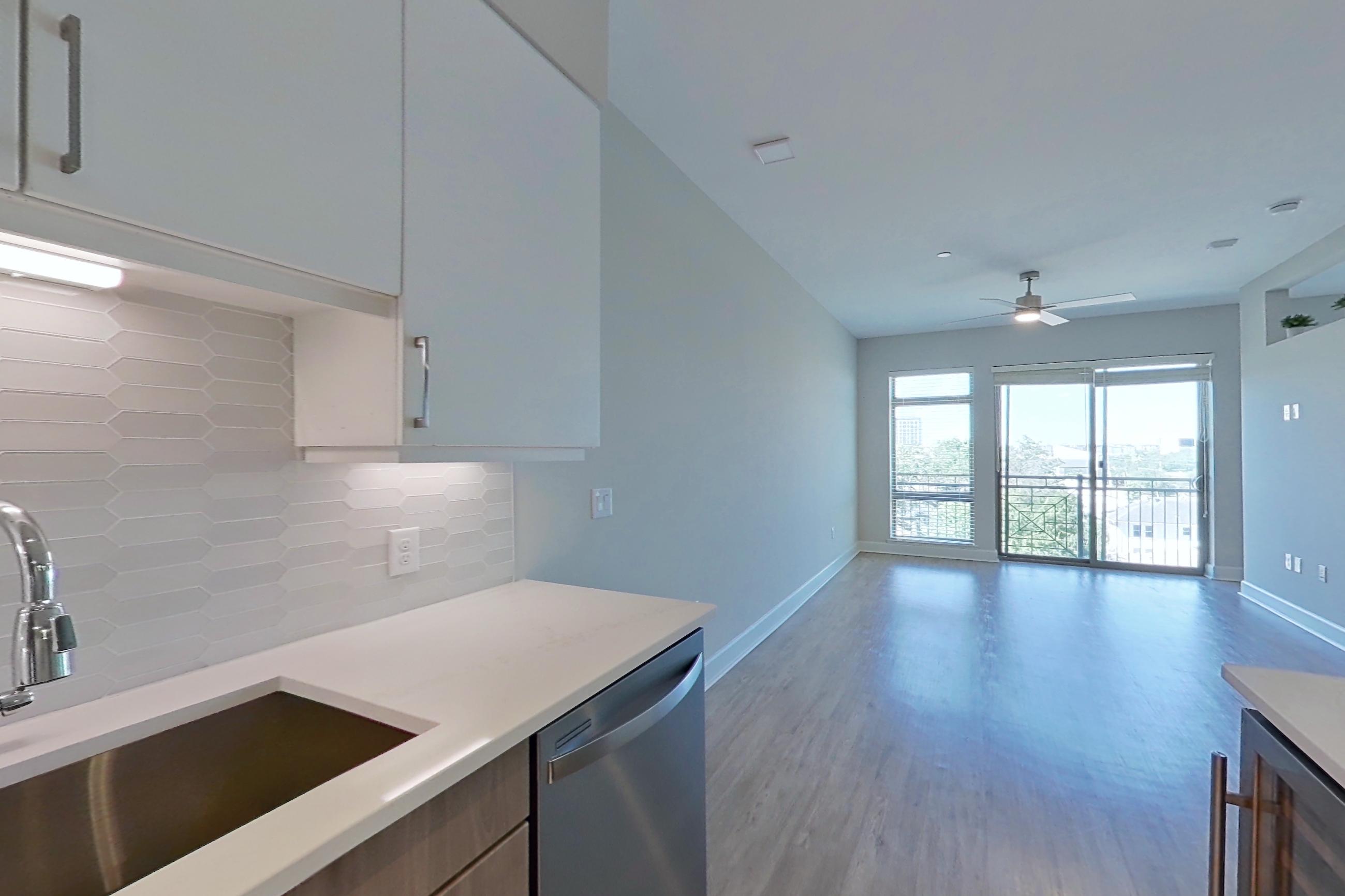 Kitchen with dishwasher, gas range, light countertops, light wood-finish flooring, oven/range, range hood, refrigerator, and stainless steel appliances, Apartment 534 at Montrose at Buffalo Bayou
