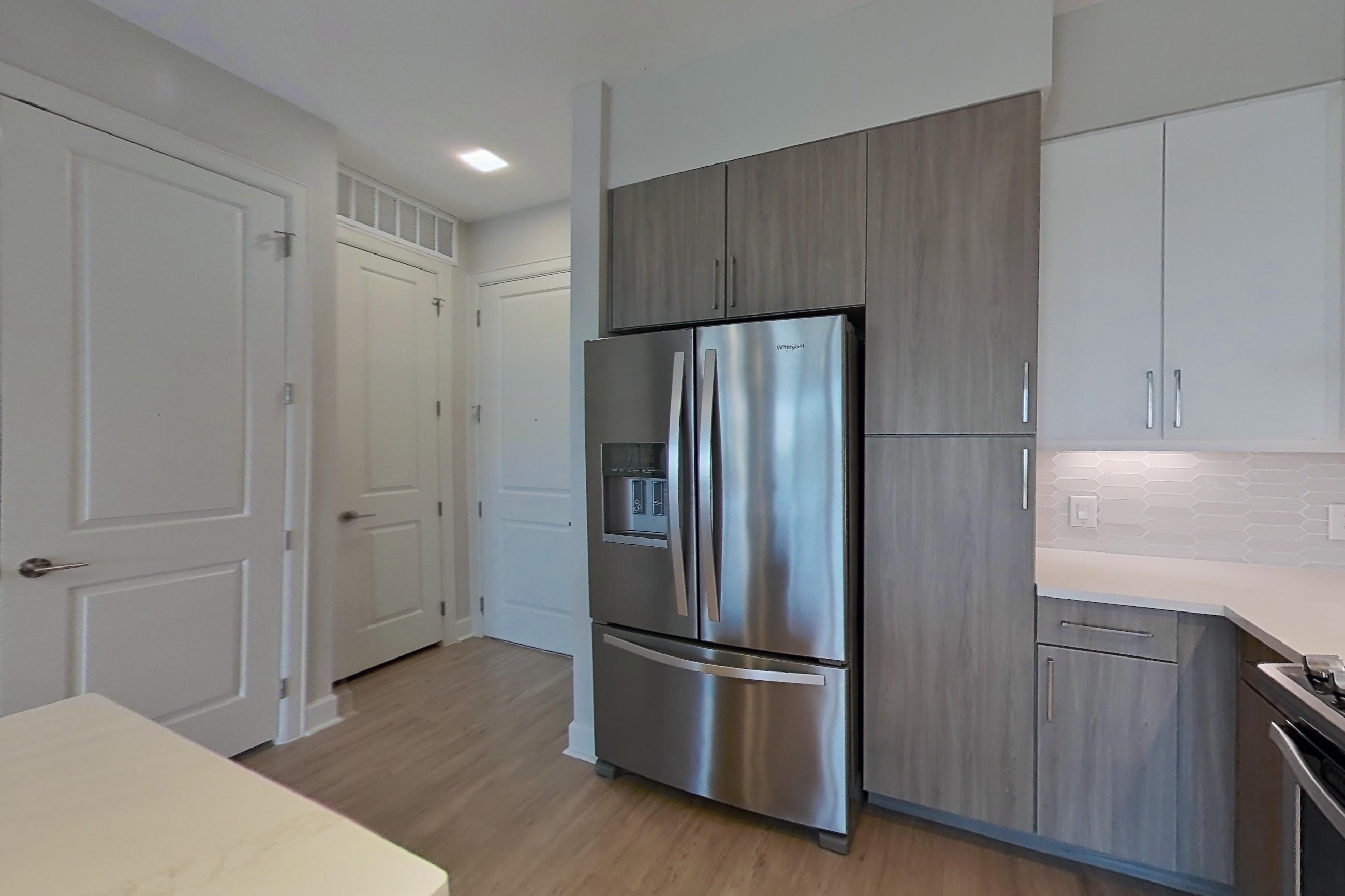Kitchen with dishwasher, gas range, light countertops, light wood-finish flooring, oven/range, range hood, refrigerator, and stainless steel appliances, Apartment 534 at Montrose at Buffalo Bayou