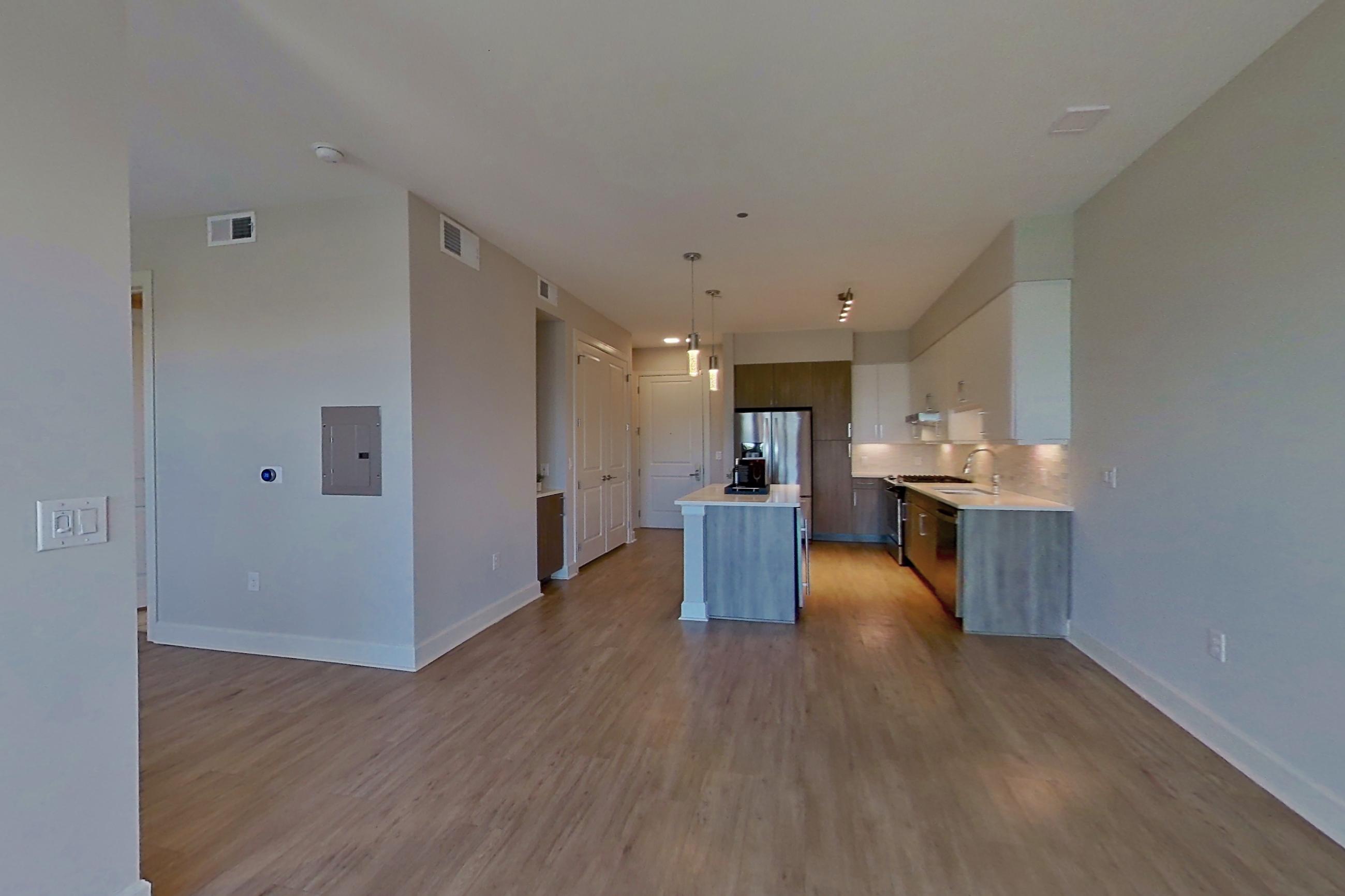 Living room with kitchen island, light countertops, and light wood-finish flooring, Apartment 534 at Montrose at Buffalo Bayou