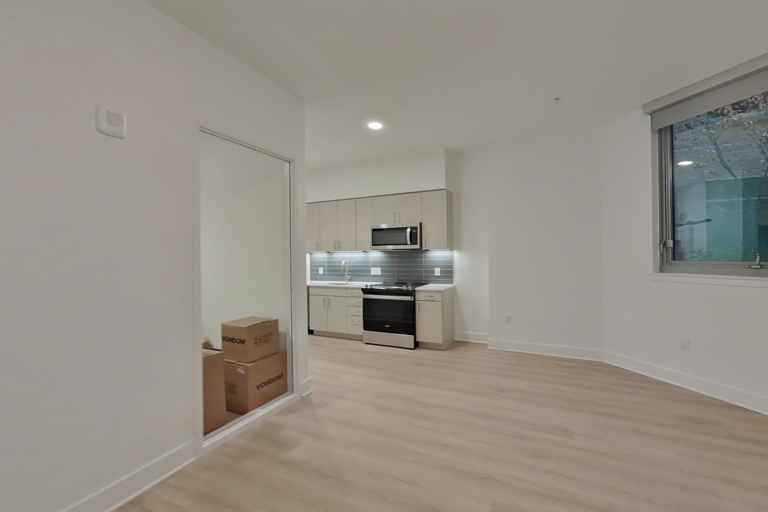Living space with electric range and light wood-finish flooring, Apartment 116 at SoNYa