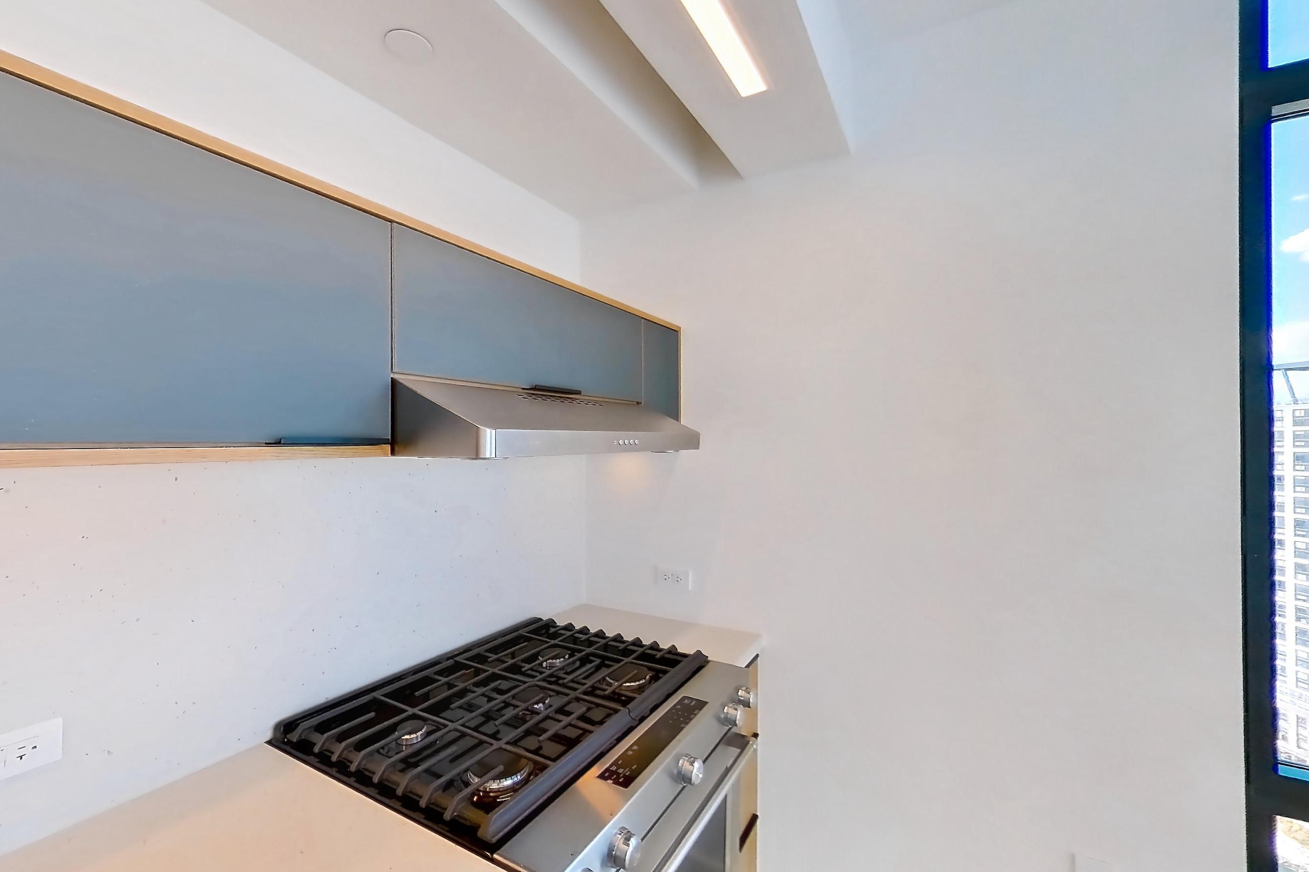 Kitchen with city view, gas range, light stone countertops, light wood-finish flooring, oven/range, and stainless steel appliances, Apartment 0-PHF at The Bellslip