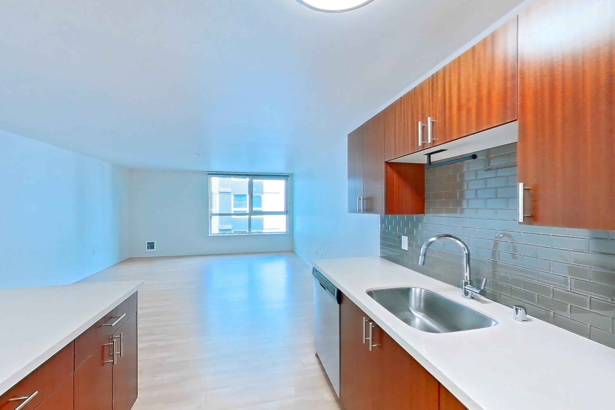 Kitchen island with dishwasher, electric range, light countertops, light stone countertops, light wood-finish flooring, oven/range, refrigerator, and stainless steel appliances, Apartment L513 at Union SLU