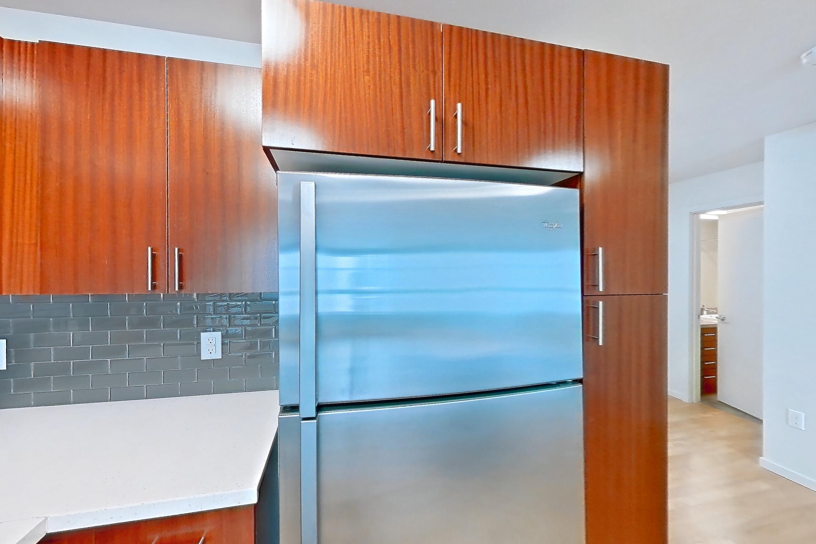 Kitchen island with dishwasher, electric range, light countertops, light stone countertops, light wood-finish flooring, oven/range, refrigerator, and stainless steel appliances, Apartment L513 at Union SLU