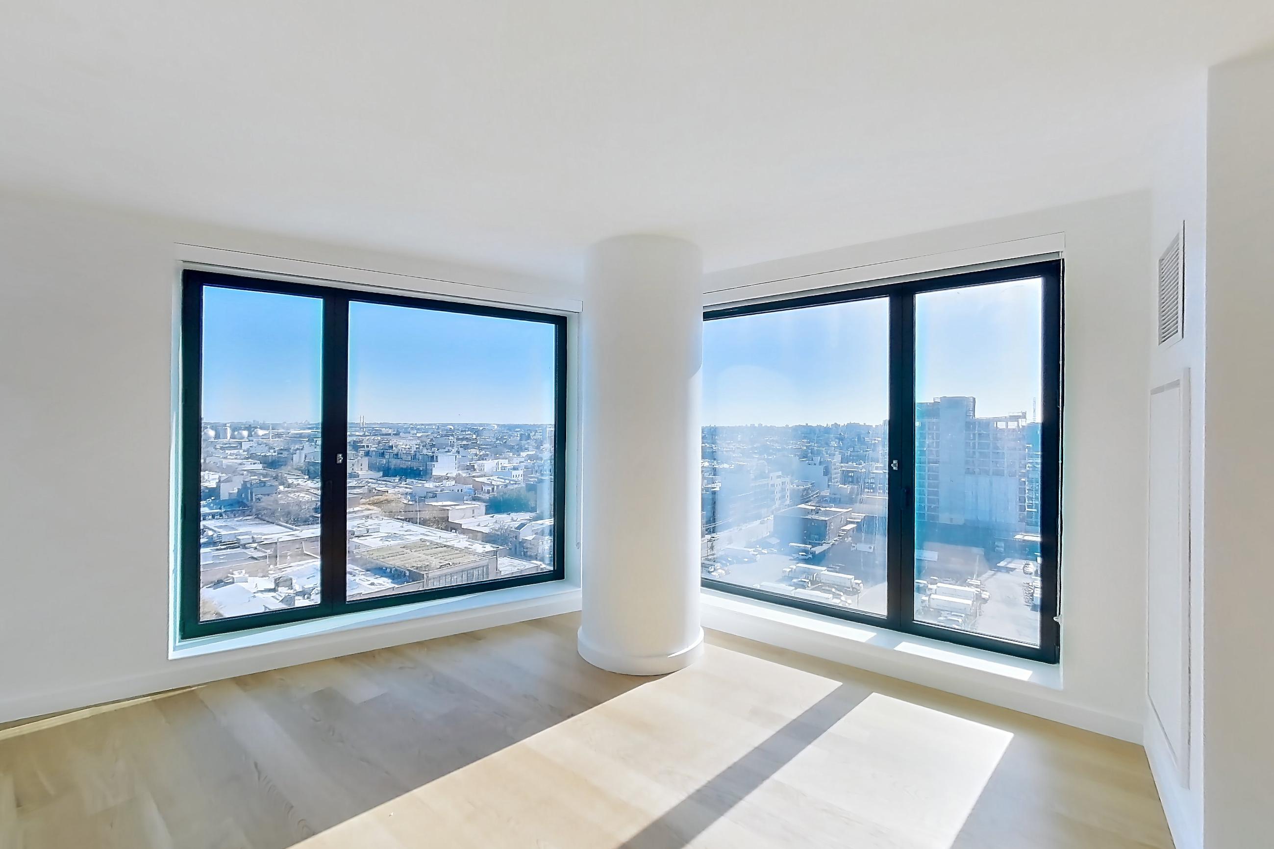 Living room with city view, light wood-finish flooring, oven/range, and stainless steel appliances, Apartment 1-1509 at Eagle + West