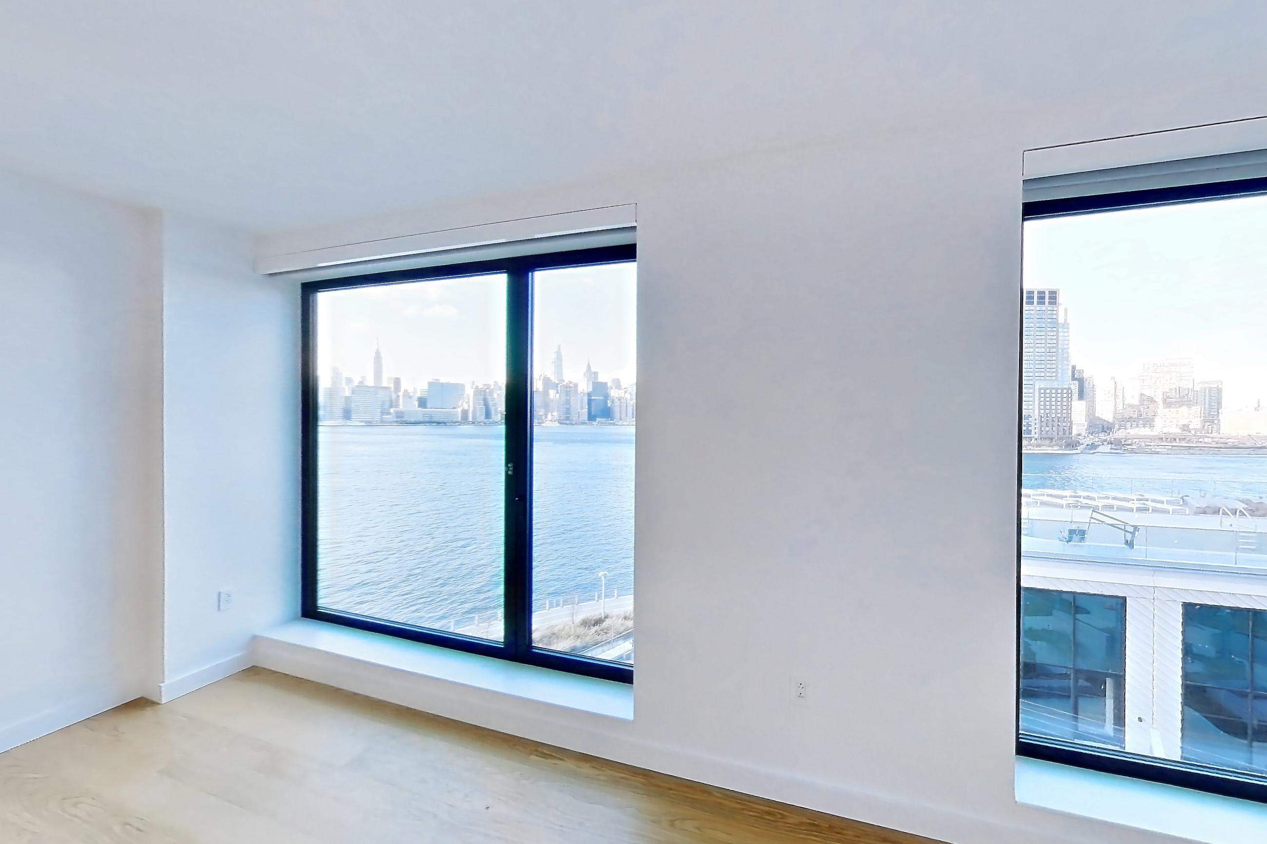Living room with city view, light wood-finish flooring, and water view, Apartment 506 at Eagle + West