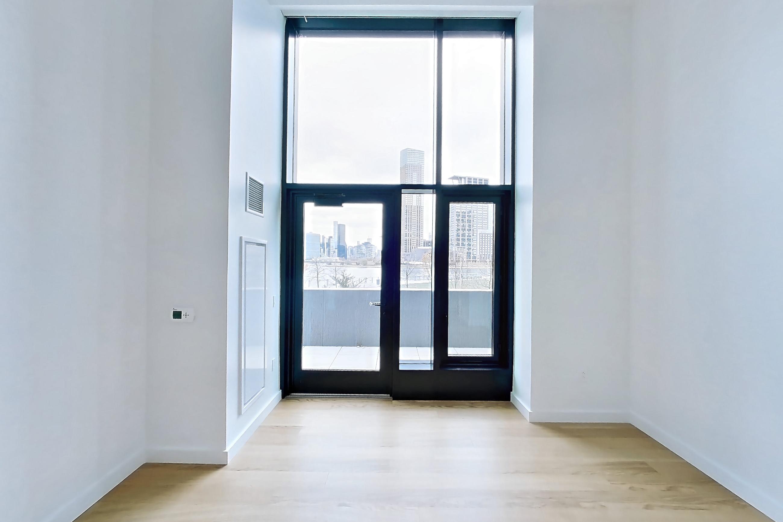 Living room with city view and light wood-finish flooring, Apartment 1-0110 at Eagle + West