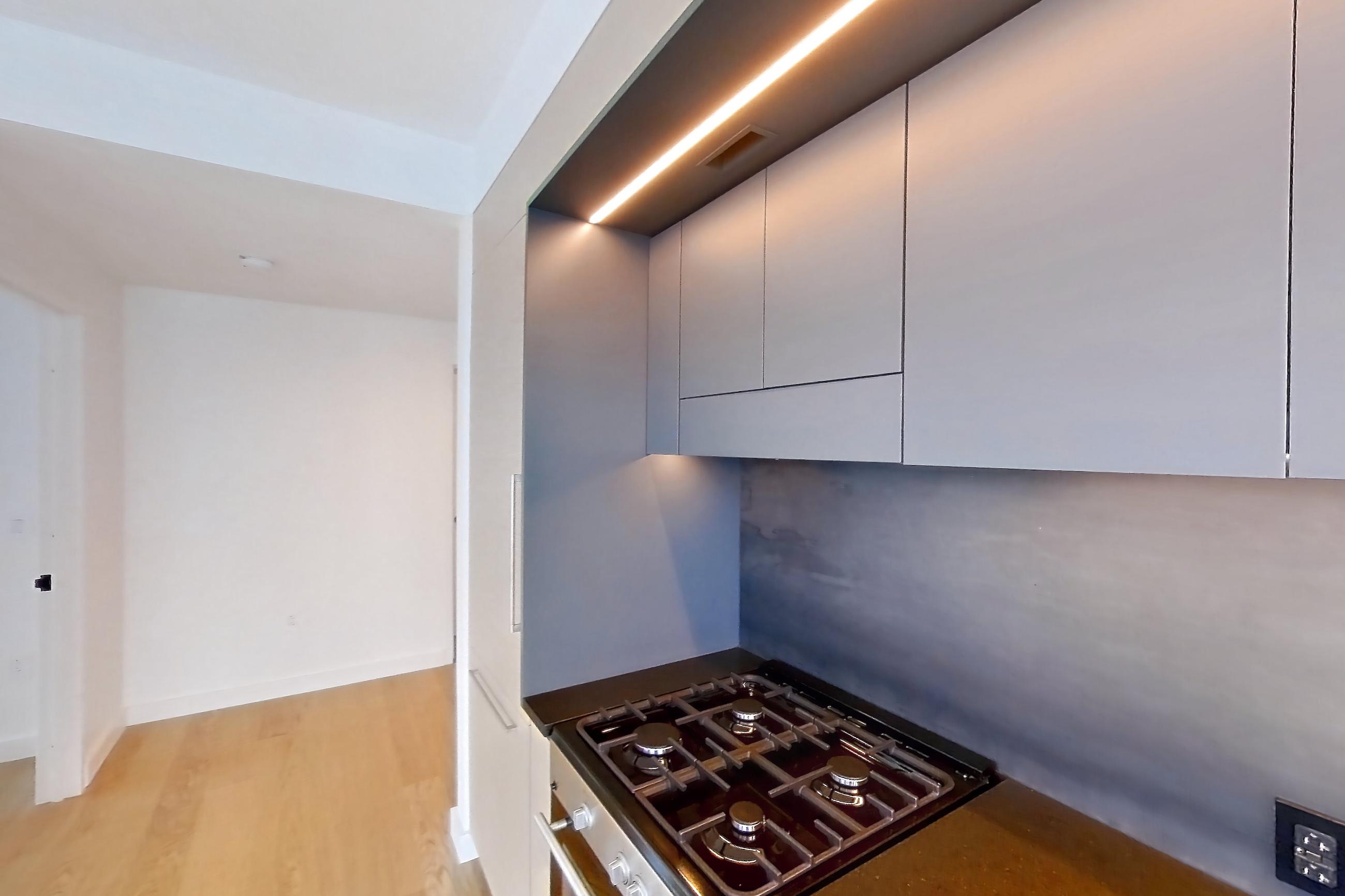 Kitchen with gas cooktop and light wood-finish flooring, Apartment 1-1604 at Eagle + West