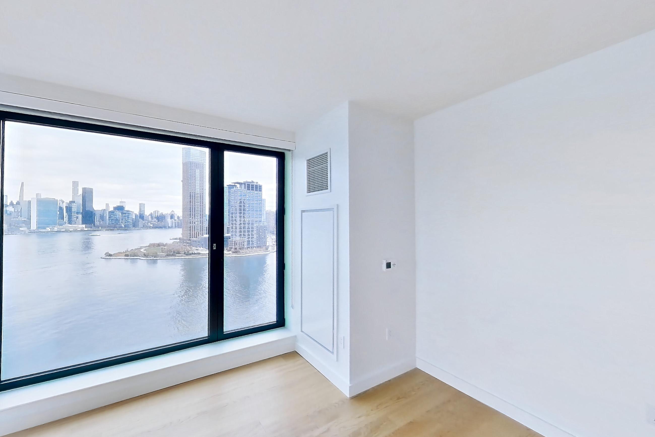 Living room with city view, light wood-finish flooring, and water view, Apartment 1-1604 at Eagle + West