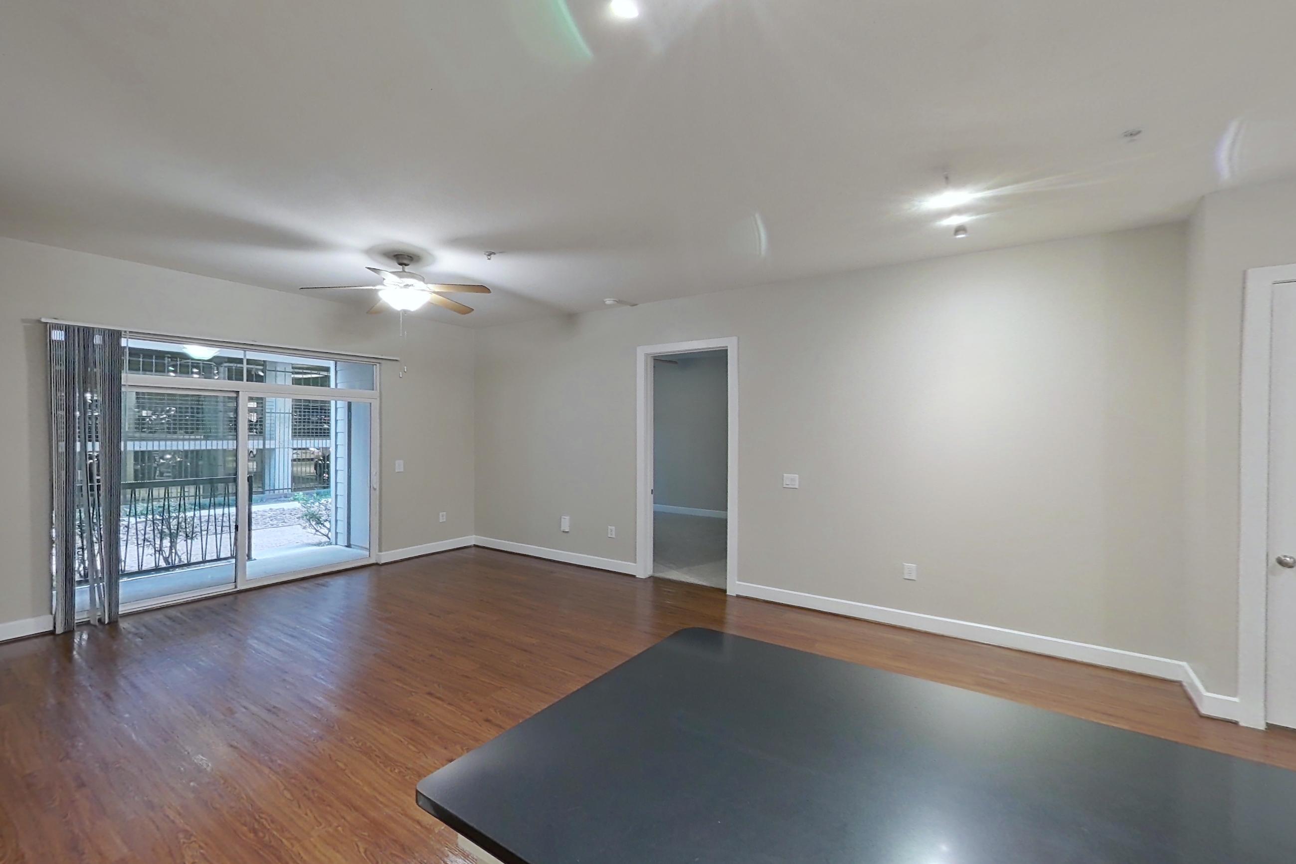 Kitchen with dark countertops, dark stone countertops, dark wood-finish flooring, dishwasher, electric range, light wood-finish flooring, microwave, oven/range, refrigerator, and stainless steel appliances, Apartment 160 at Domain at CityCentre