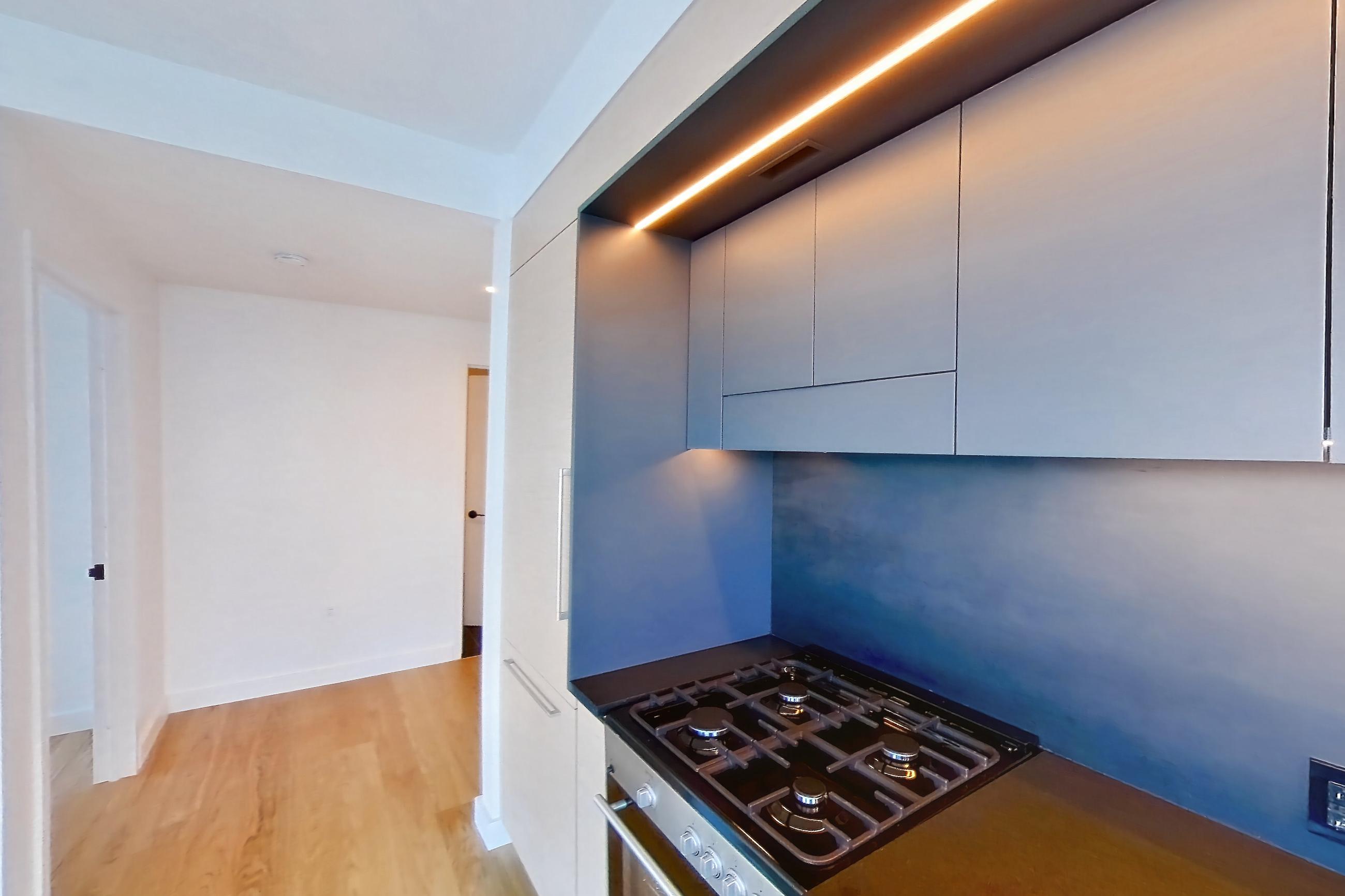 Kitchen with gas range and light wood-finish flooring, Apartment 1-2204 at Eagle + West