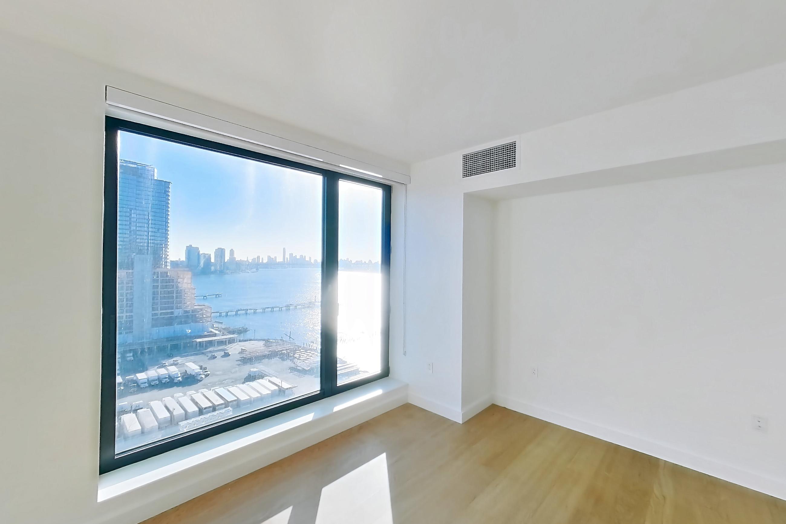 Living space with light wood-finish flooring and water view, Apartment 1-1801 at Eagle + West