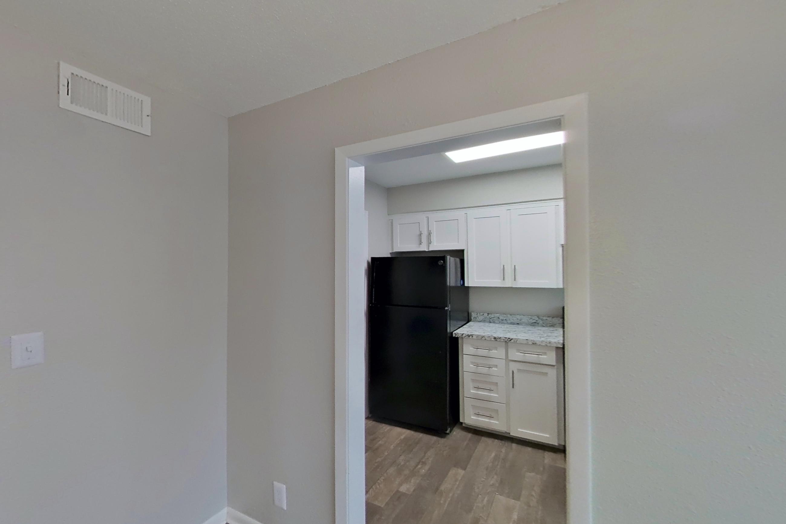 Dining room with black appliances, dark wood-finish flooring, and refrigerator, Apartment 1402D at The Life at Legacy Fountains