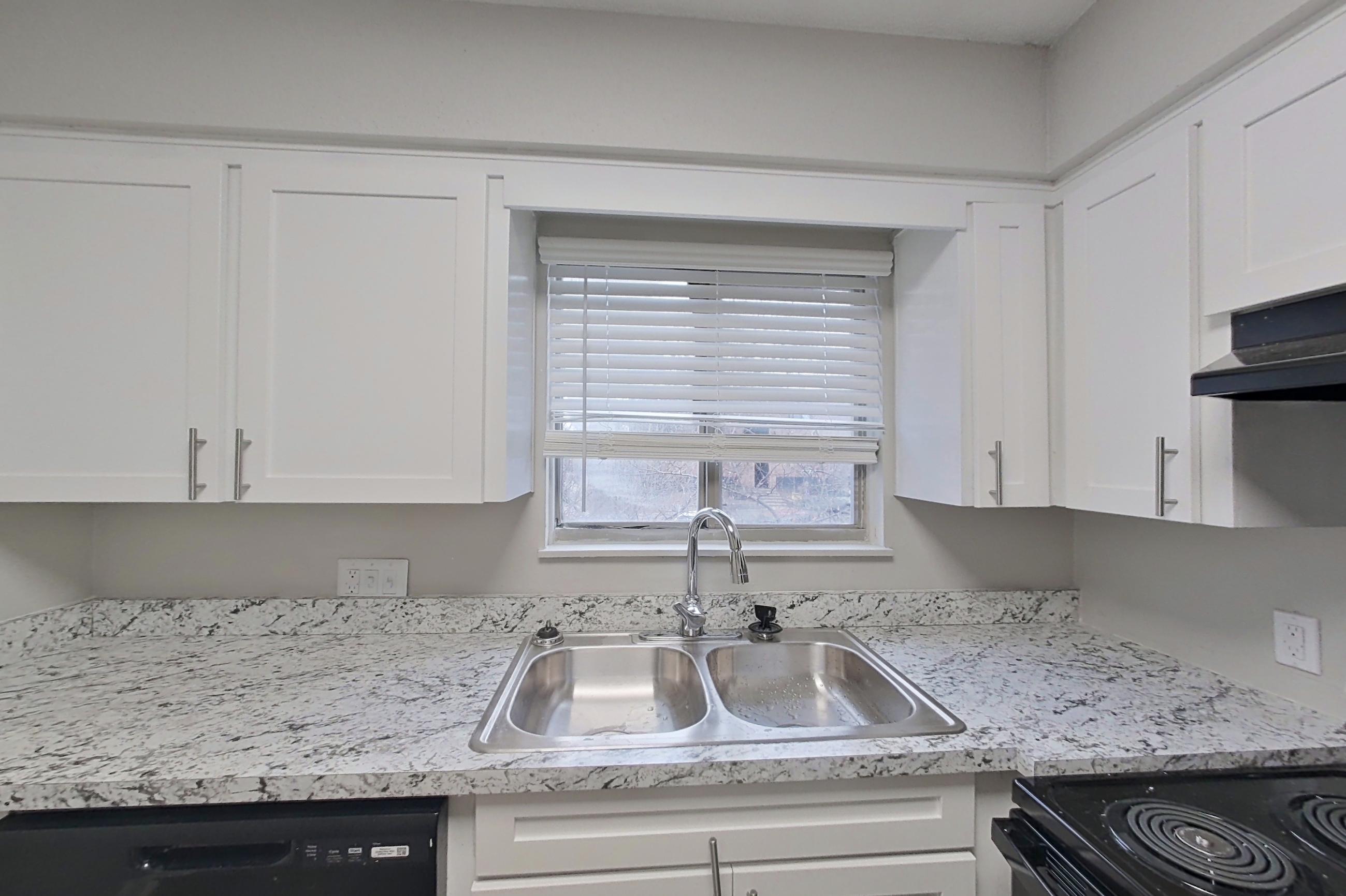 Kitchen with black appliances, dishwasher, electric range, light stone countertops, oven/range, range hood, and refrigerator, Apartment 1412C at The Life at Legacy Fountains