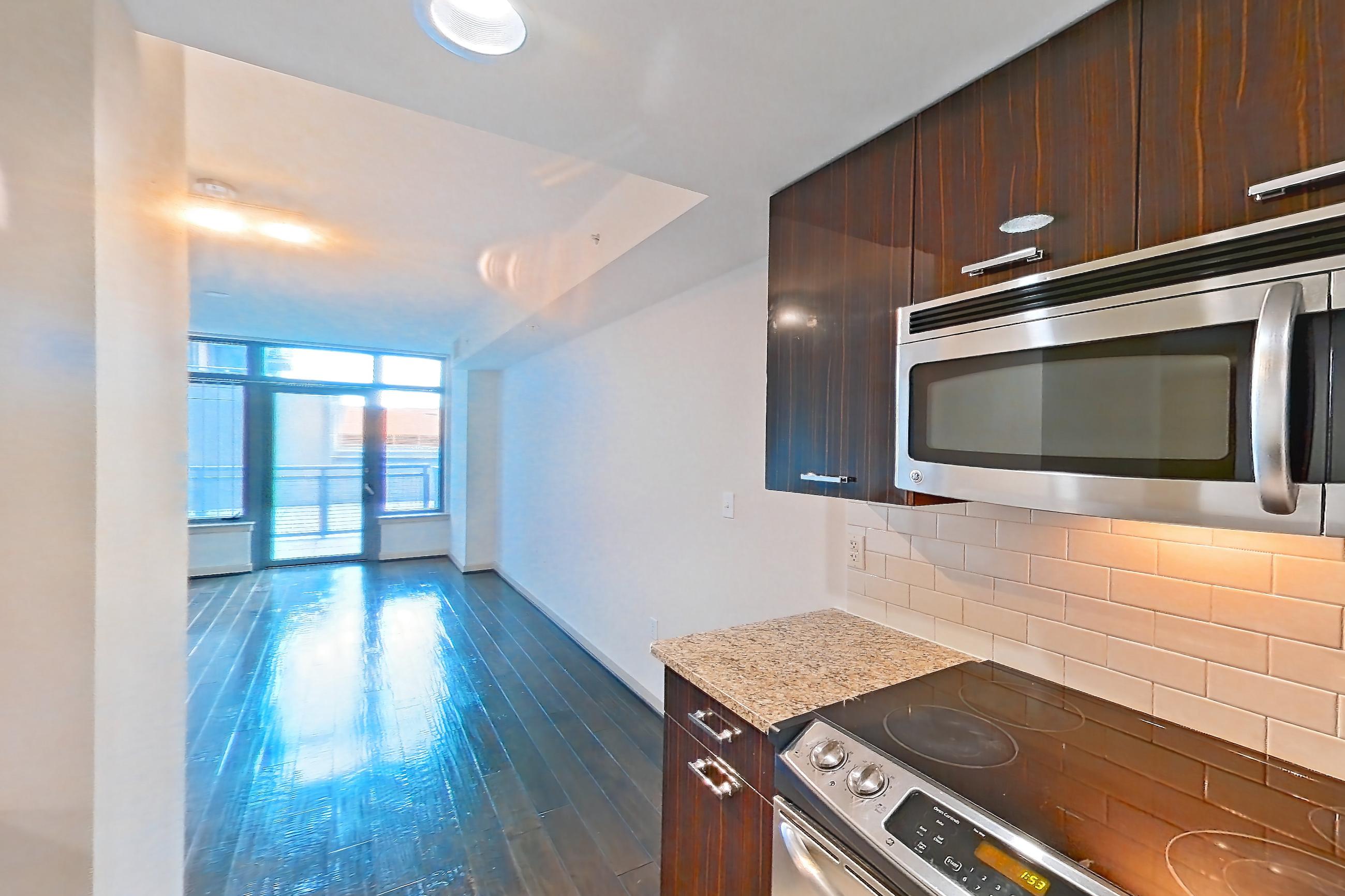 Kitchen with electric range, light stone countertops, oven/range, and stainless steel appliances, Apartment 0413 at The Cameron