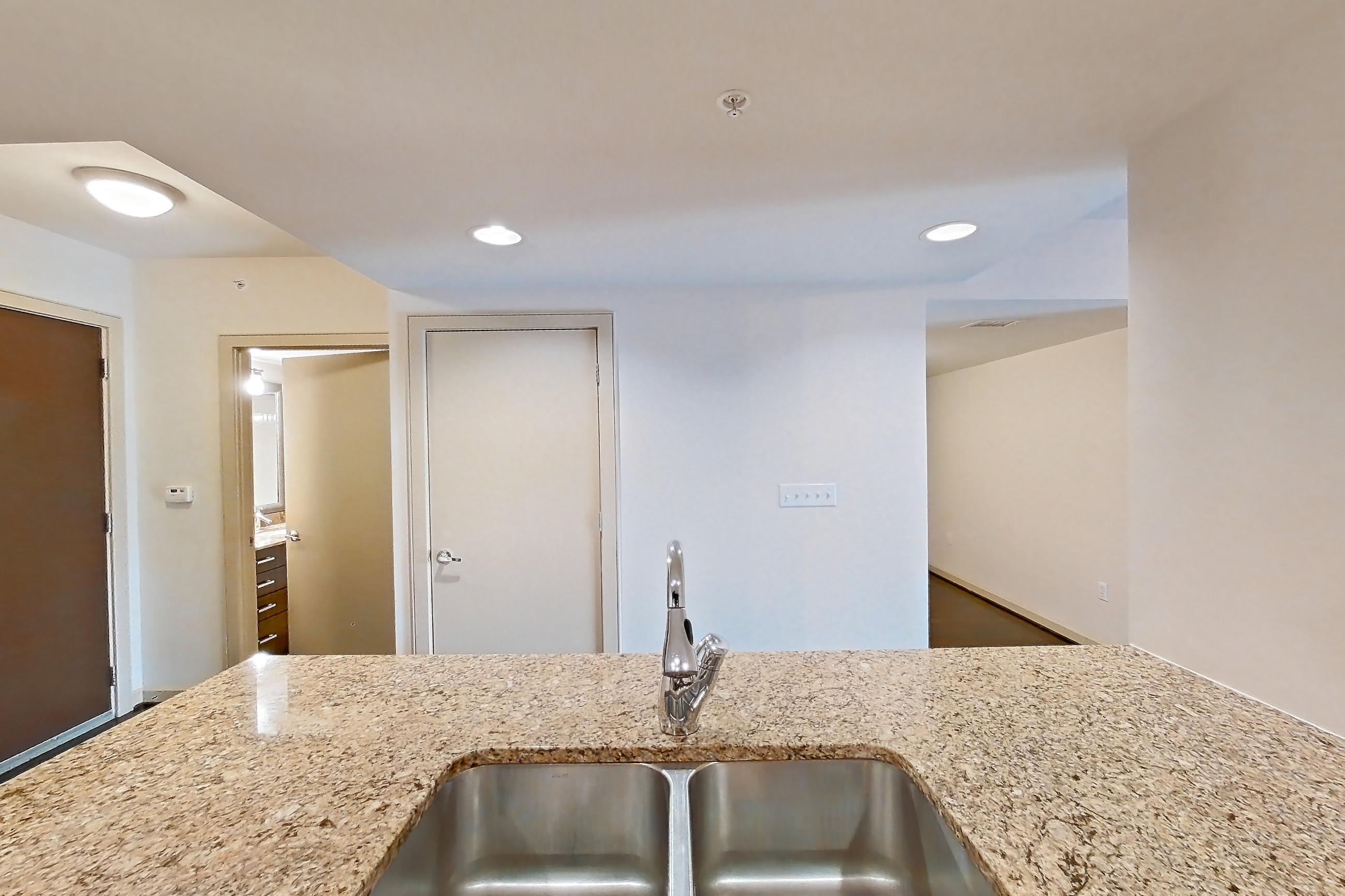 Kitchen with electric range, light stone countertops, oven/range, and stainless steel appliances, Apartment 0413 at The Cameron