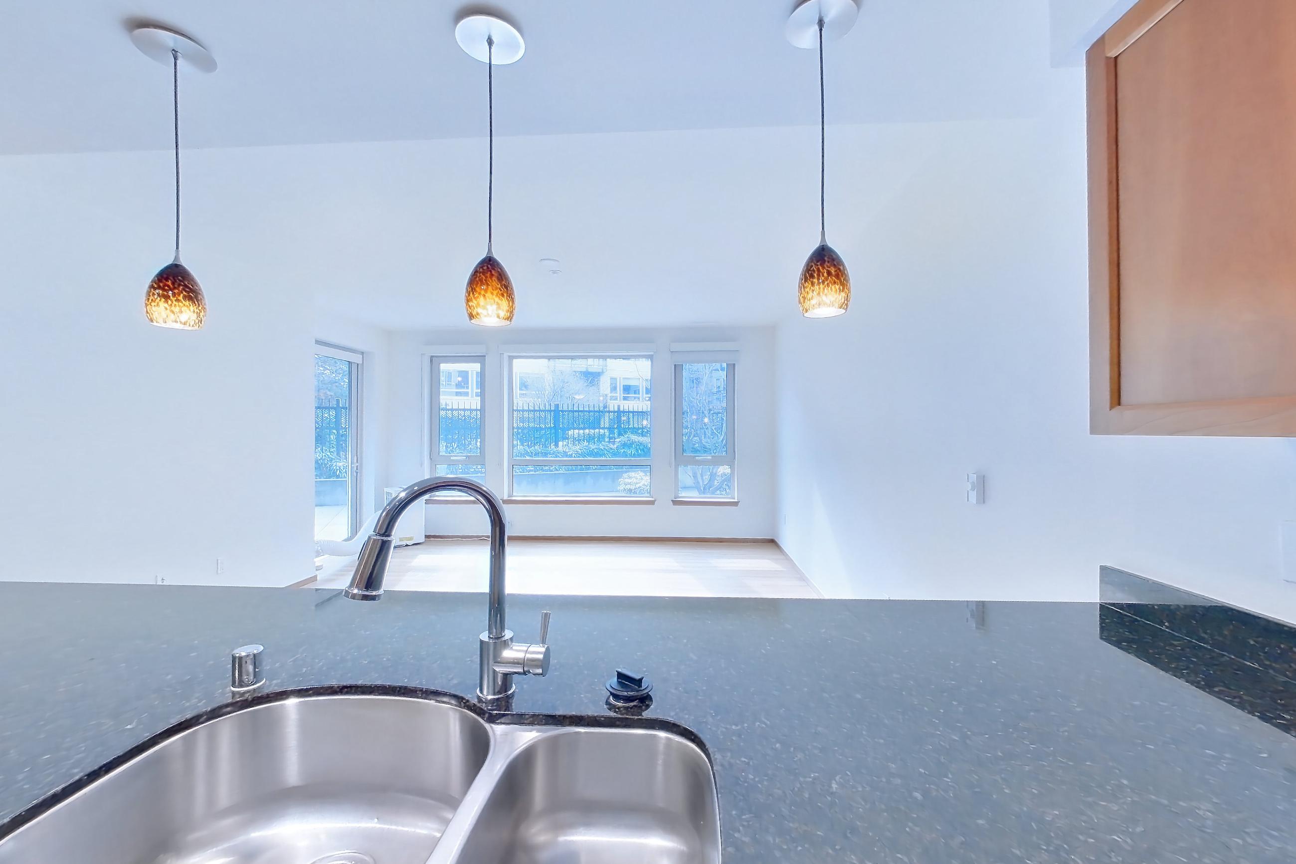 Kitchen with dark stone countertops, electric range, light wood-finish flooring, oven/range, and stainless steel appliances, Apartment B245 at 77 Central