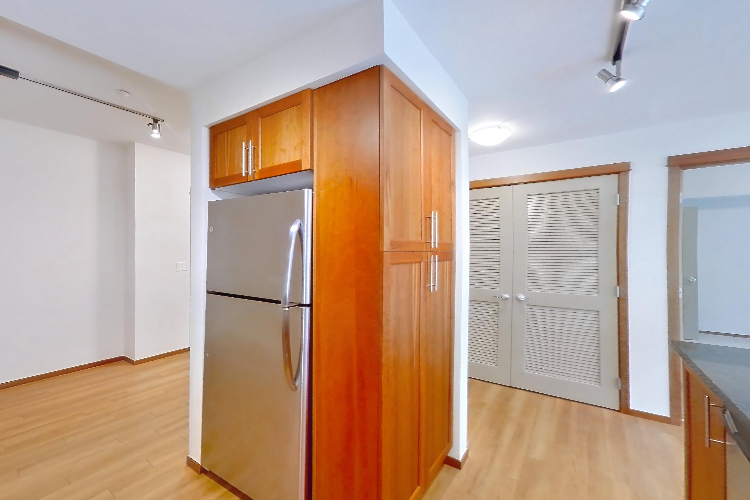 Kitchen with dark stone countertops, electric range, light wood-finish flooring, oven/range, and stainless steel appliances, Apartment B245 at 77 Central