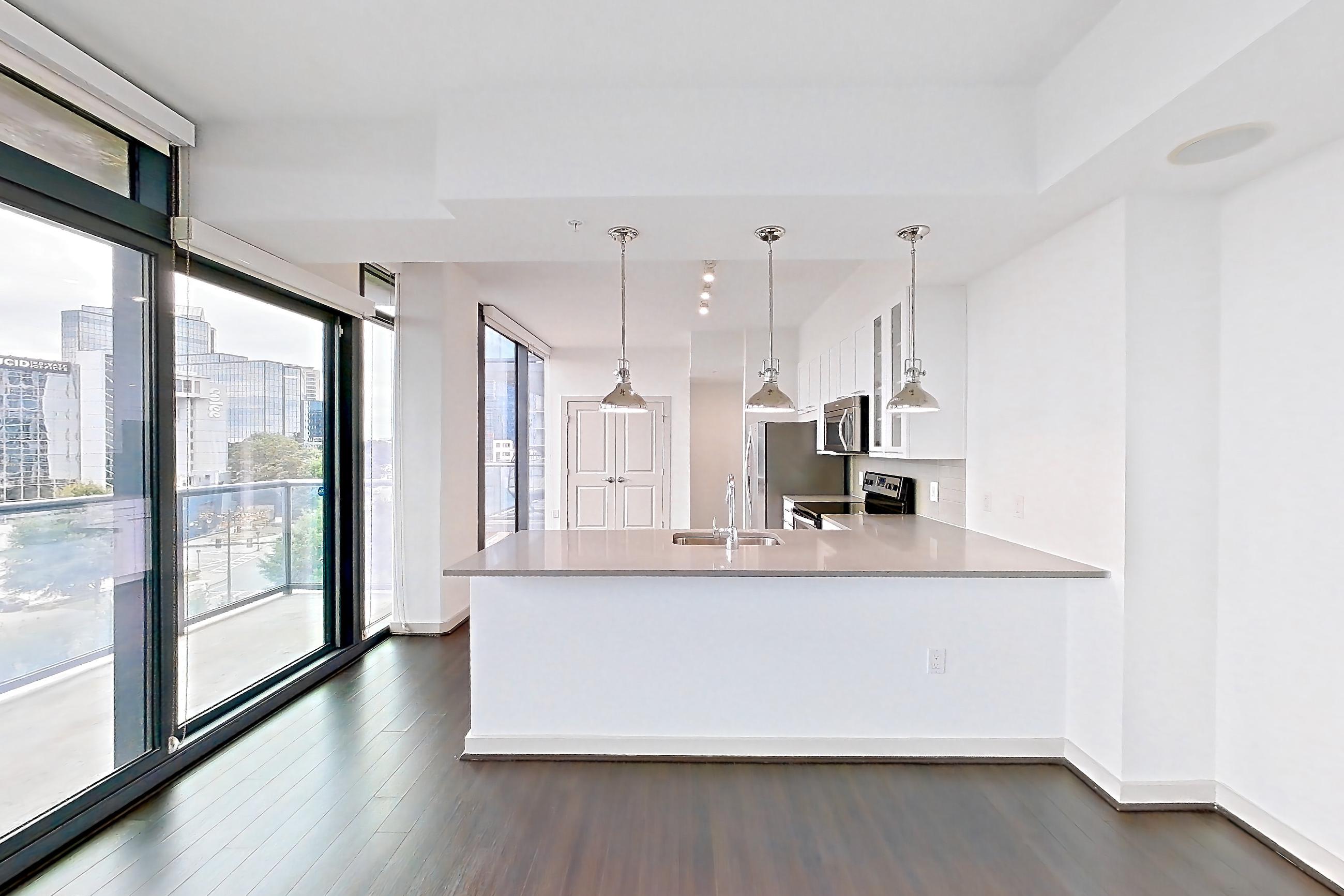 Living room with city view, dark wood-finish flooring, electric range, light countertops, oven/range, and stainless steel appliances, Apartment 0915 at Cyan on Peachtree