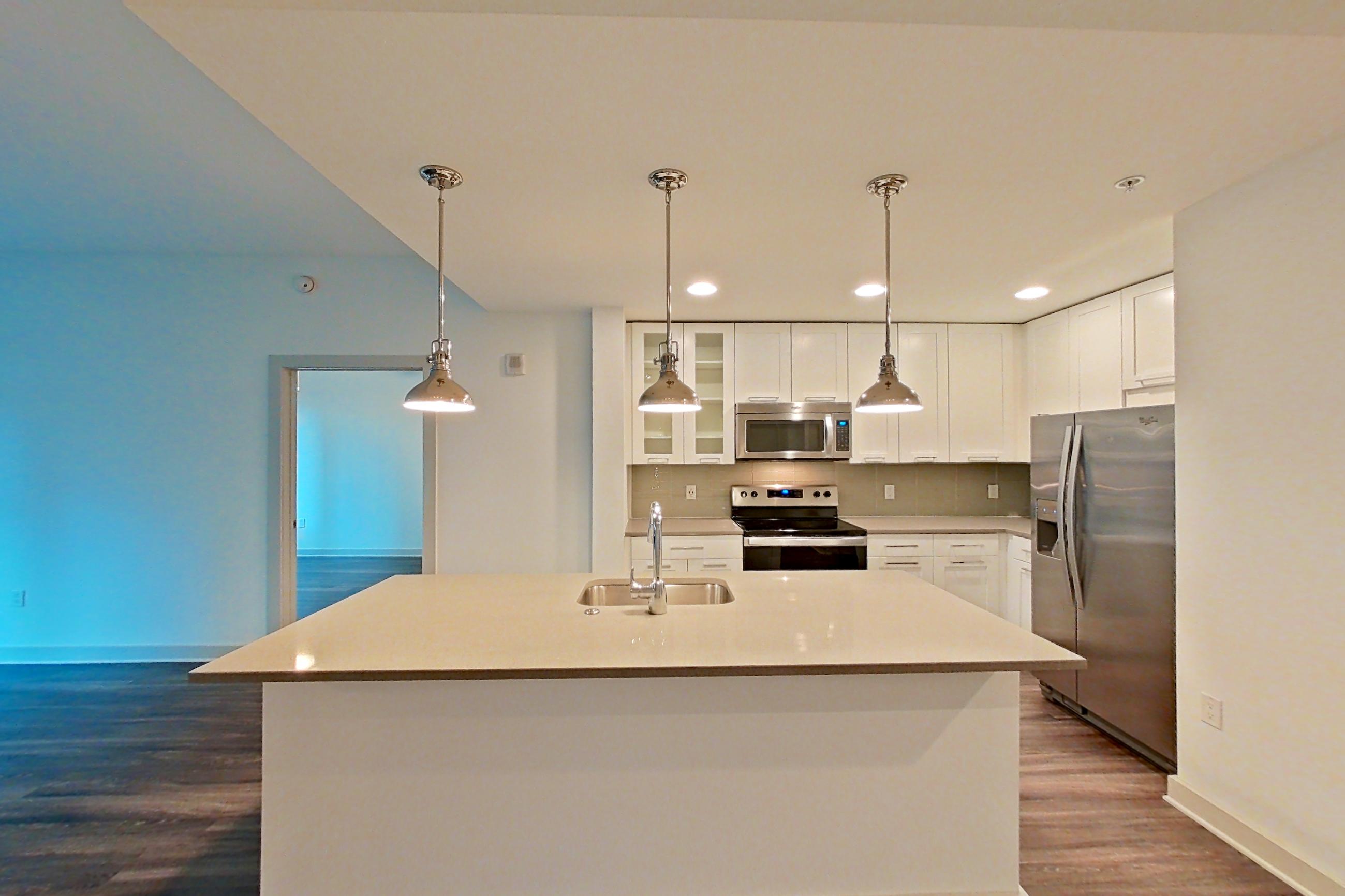 Dining area with dark wood-finish flooring, electric range, kitchen island, light countertops, oven/range, refrigerator, stainless steel appliances, and water & ice dispenser, Apartment 0206 at Cyan on Peachtree