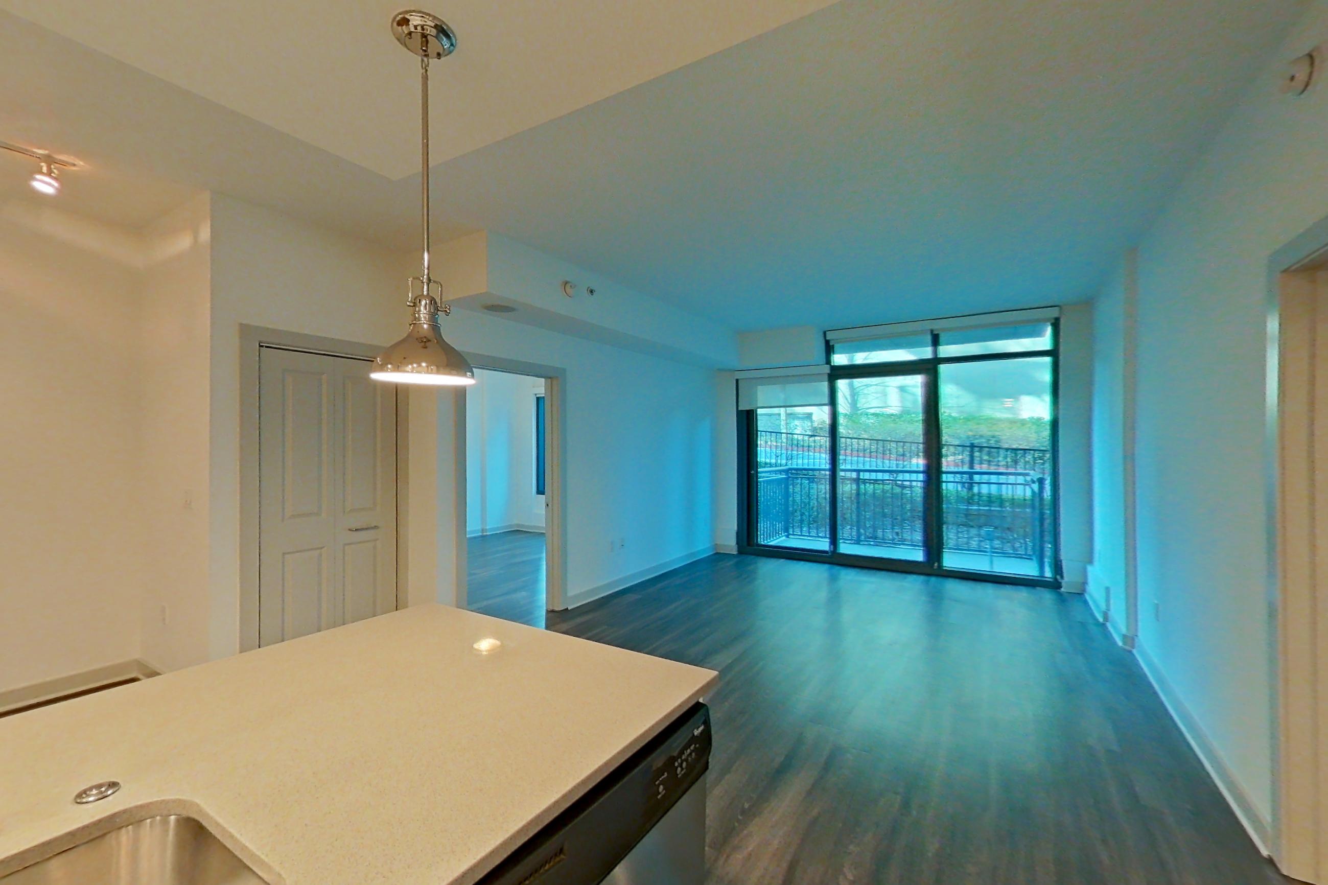 Kitchen with dark wood-finish flooring, dishwasher, electric range, light countertops, oven/range, refrigerator, stainless steel appliances, and water & ice dispenser, Apartment 0206 at Cyan on Peachtree