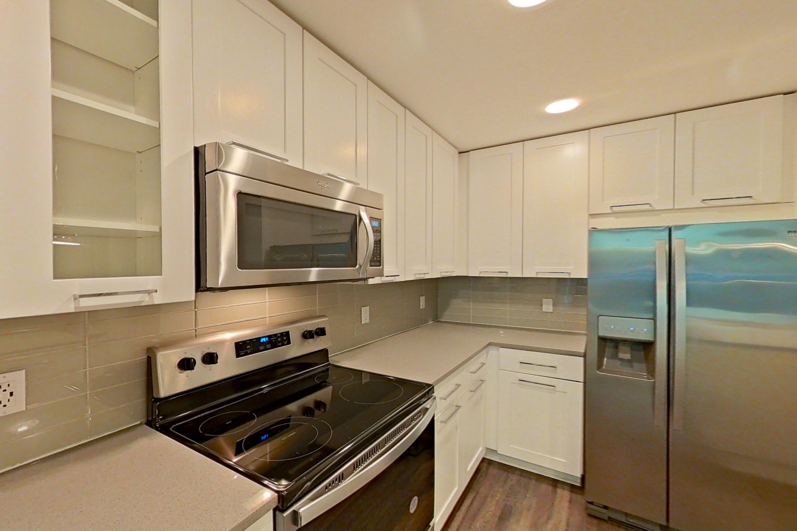 Kitchen with dark wood-finish flooring, dishwasher, electric range, light countertops, oven/range, refrigerator, stainless steel appliances, and water & ice dispenser, Apartment 0206 at Cyan on Peachtree