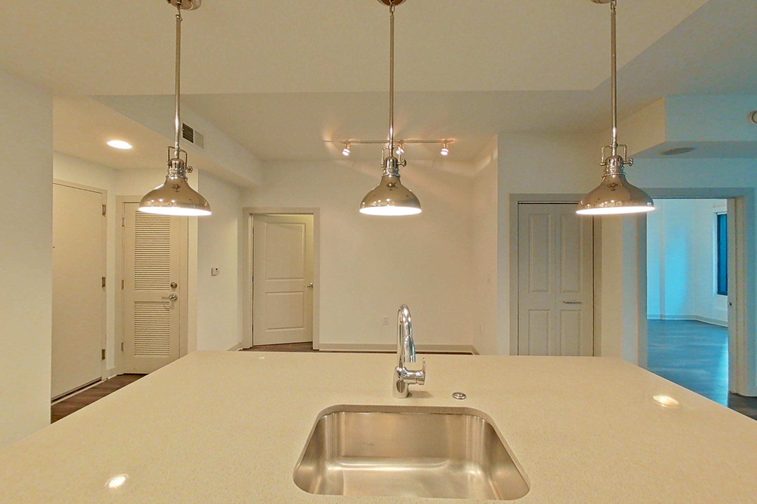 Kitchen with dark wood-finish flooring, dishwasher, electric range, light countertops, oven/range, refrigerator, stainless steel appliances, and water & ice dispenser, Apartment 0206 at Cyan on Peachtree