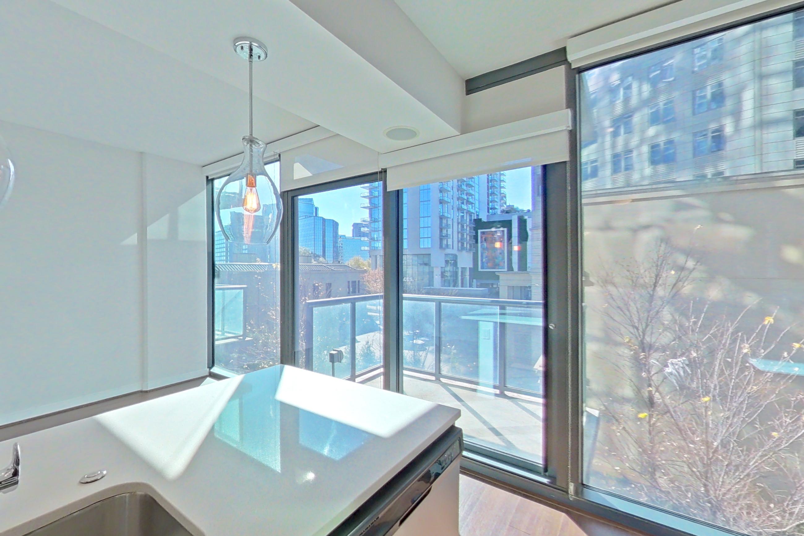 Kitchen with city view, dark wood-finish flooring, dishwasher, light countertops, refrigerator, stainless steel appliances, and water & ice dispenser, Apartment 0608 at Cyan on Peachtree