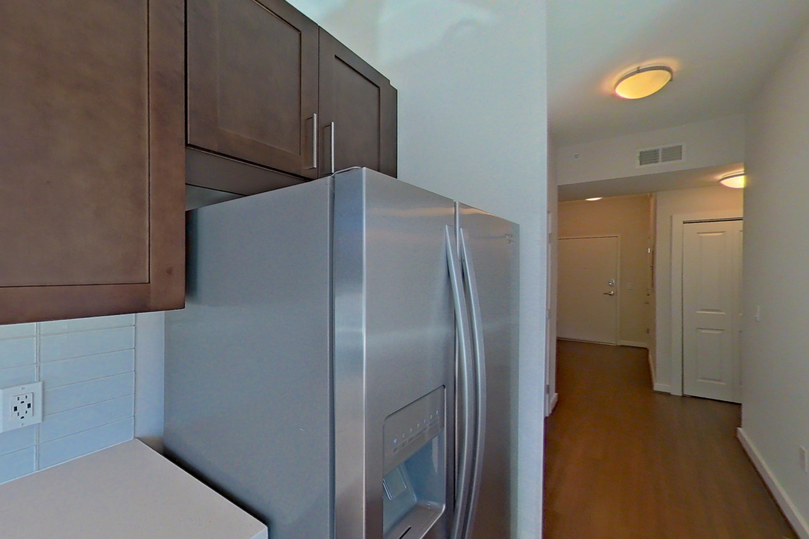 Kitchen with city view, dark wood-finish flooring, dishwasher, light countertops, refrigerator, stainless steel appliances, and water & ice dispenser, Apartment 0608 at Cyan on Peachtree
