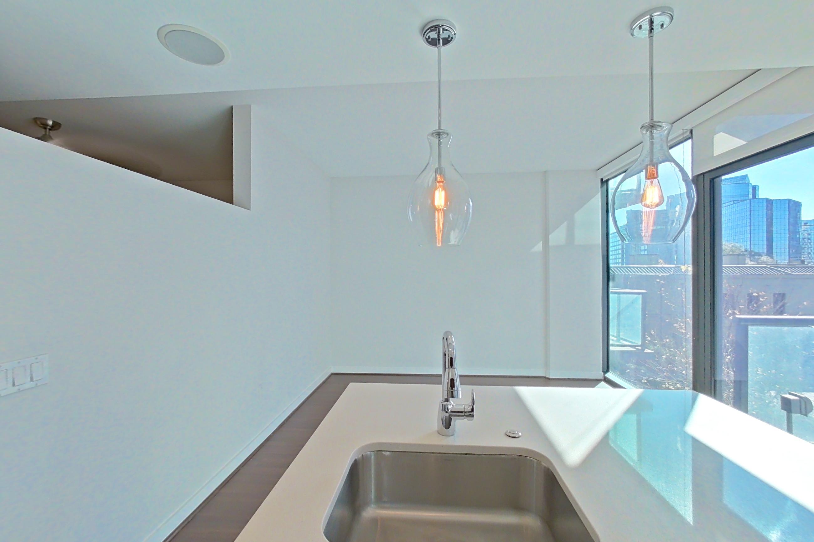 Kitchen with city view, dark wood-finish flooring, dishwasher, light countertops, refrigerator, stainless steel appliances, and water & ice dispenser, Apartment 0608 at Cyan on Peachtree