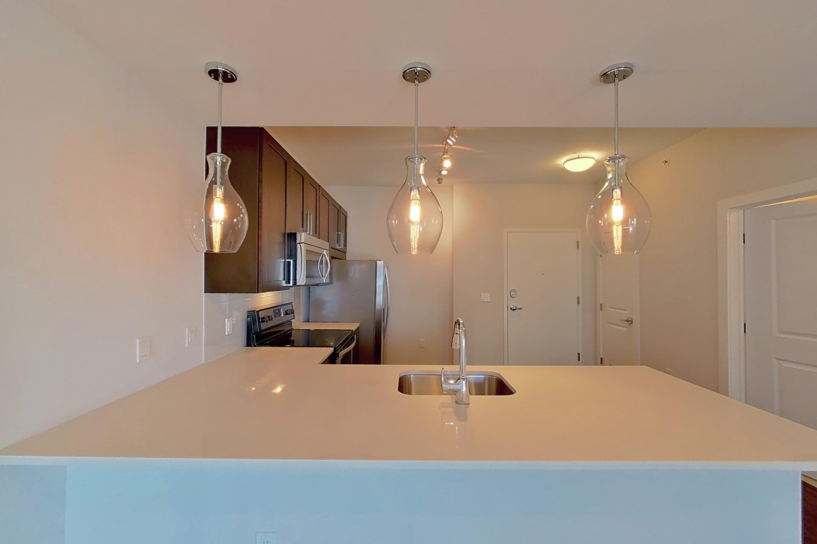 Dining area with dark wood-finish flooring, electric range, light countertops, refrigerator, and stainless steel appliances, Apartment 1011 at Cyan on Peachtree