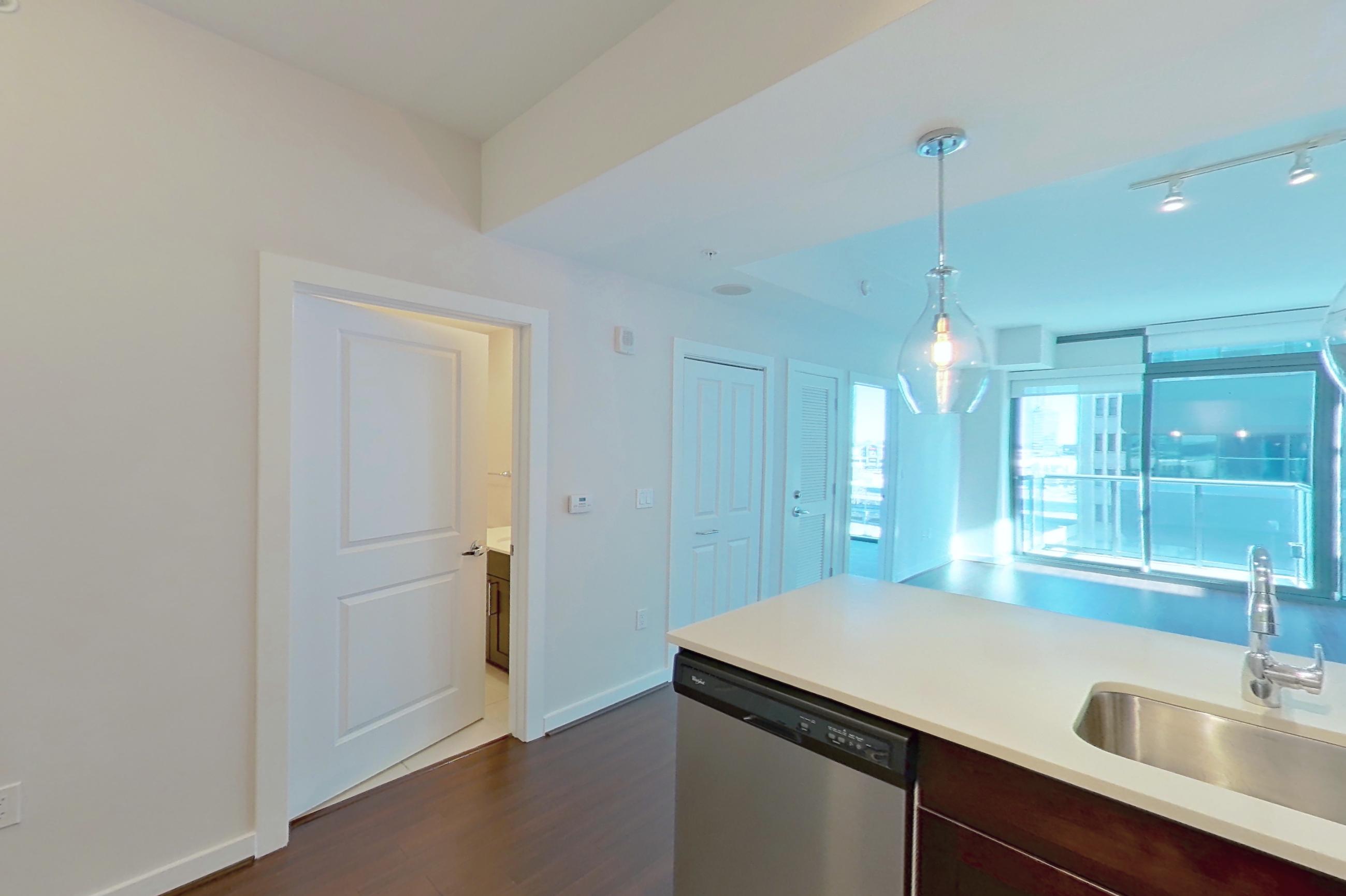 Kitchen with dark wood-finish flooring, dishwasher, electric range, light countertops, microwave, oven/range, refrigerator, stainless steel appliances, and water & ice dispenser, Apartment 1011 at Cyan on Peachtree