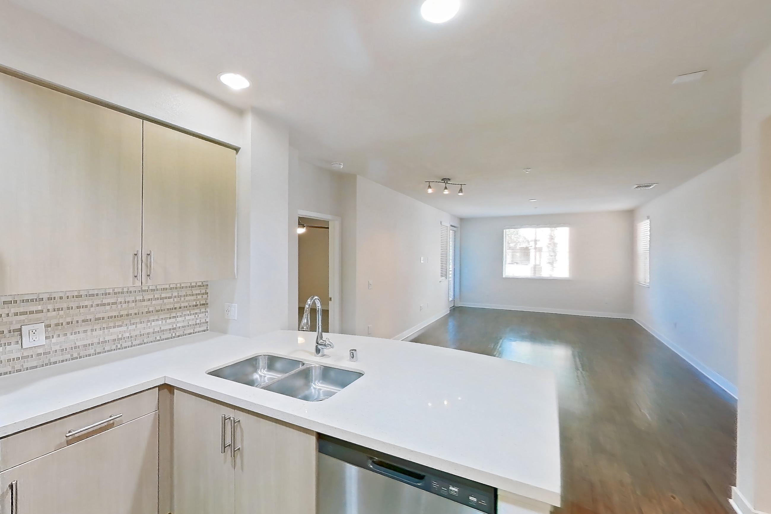 Kitchen with dishwasher, gas range, light countertops, light stone countertops, light wood-finish flooring, microwave, oven/range, refrigerator, and stainless steel appliances, Apartment 1218 at The Verge Apartments