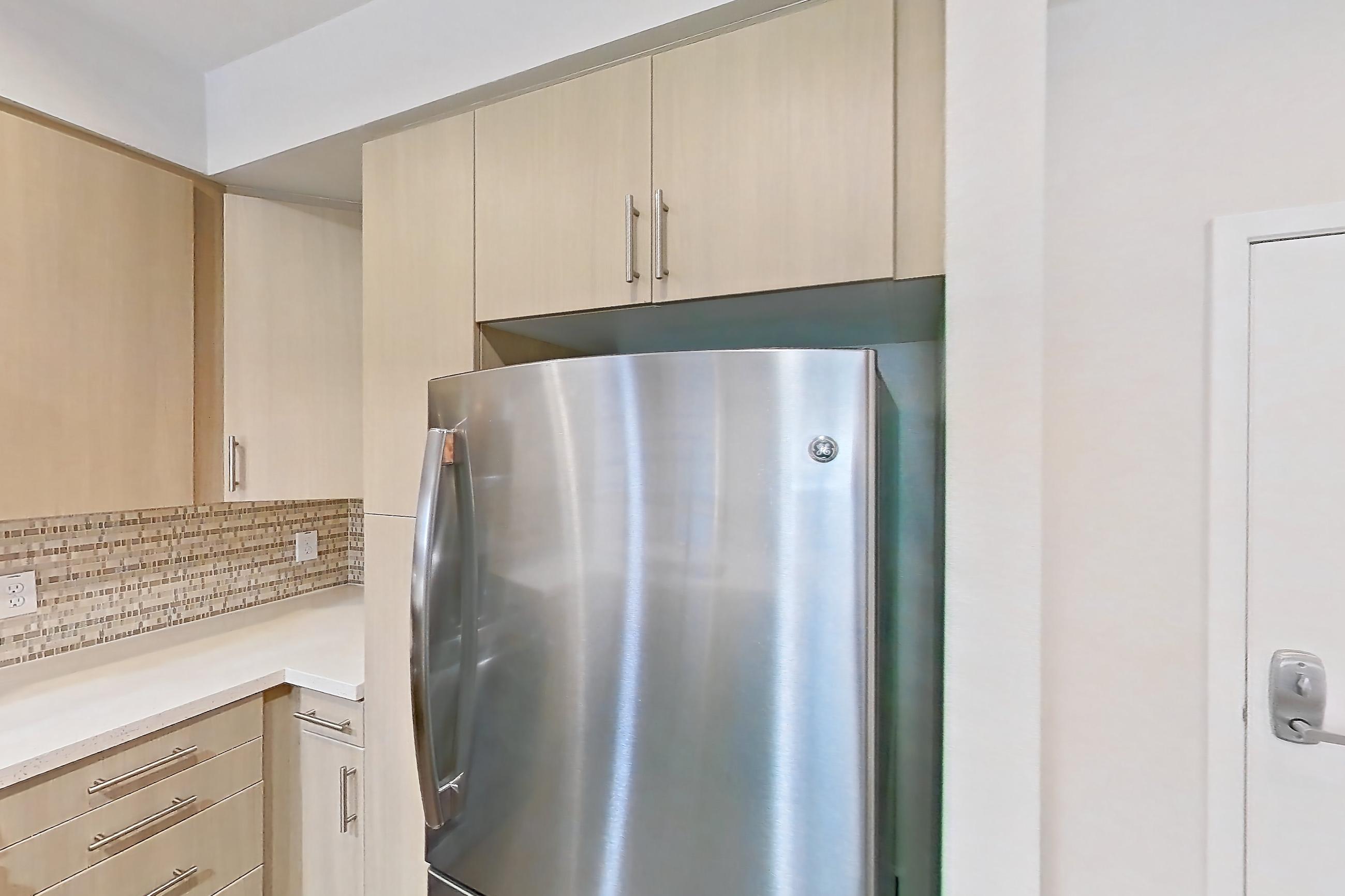 Kitchen with dark wood-finish flooring, dishwasher, gas range, light countertops, light wood-finish flooring, microwave, oven/range, refrigerator, and stainless steel appliances, Apartment 2576 at The Verge Apartments