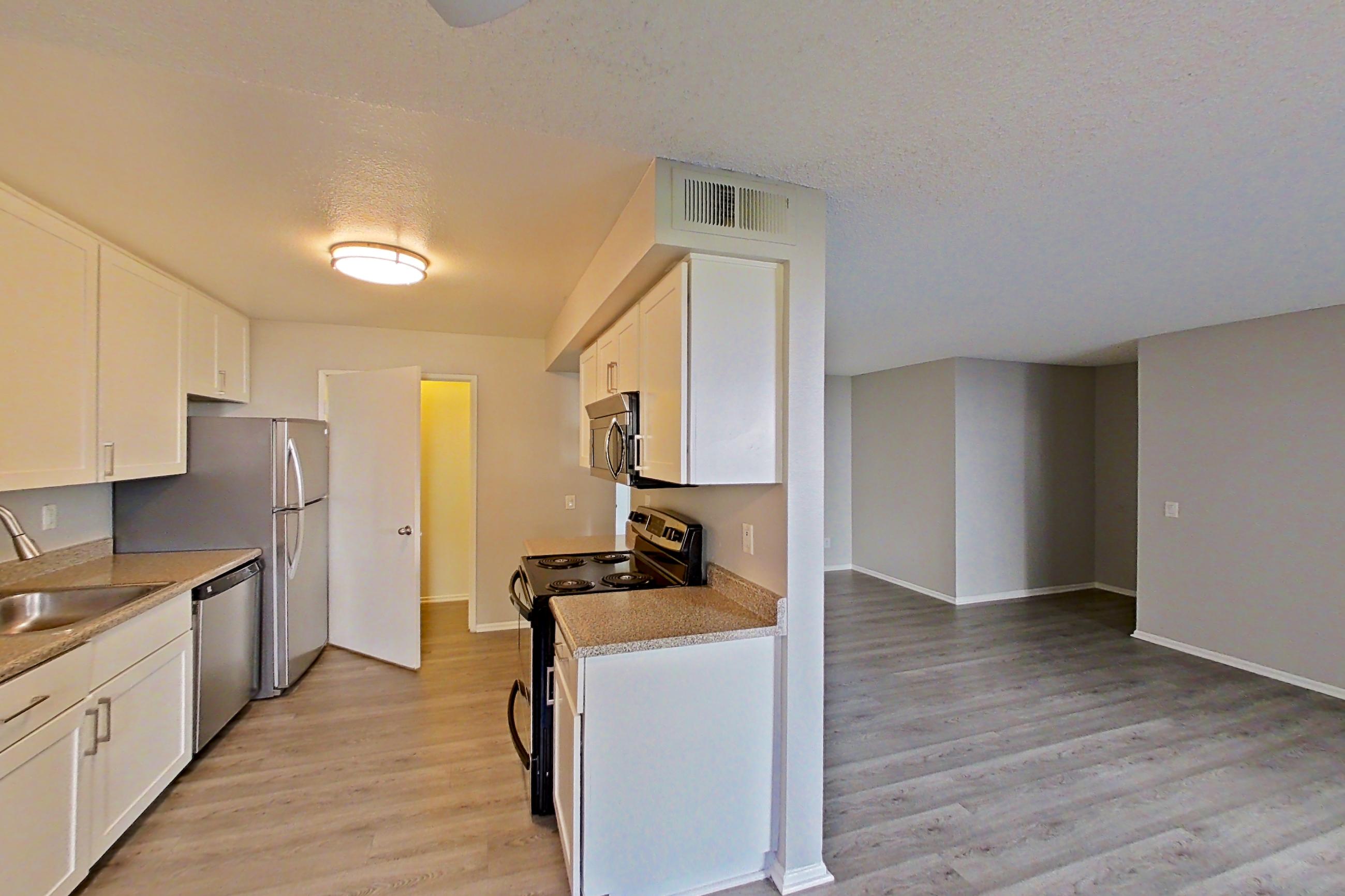 Dining area with electric range, light countertops, light stone countertops, and light wood-finish flooring, Apartment 01-02 at Avana Rancho Cucamonga