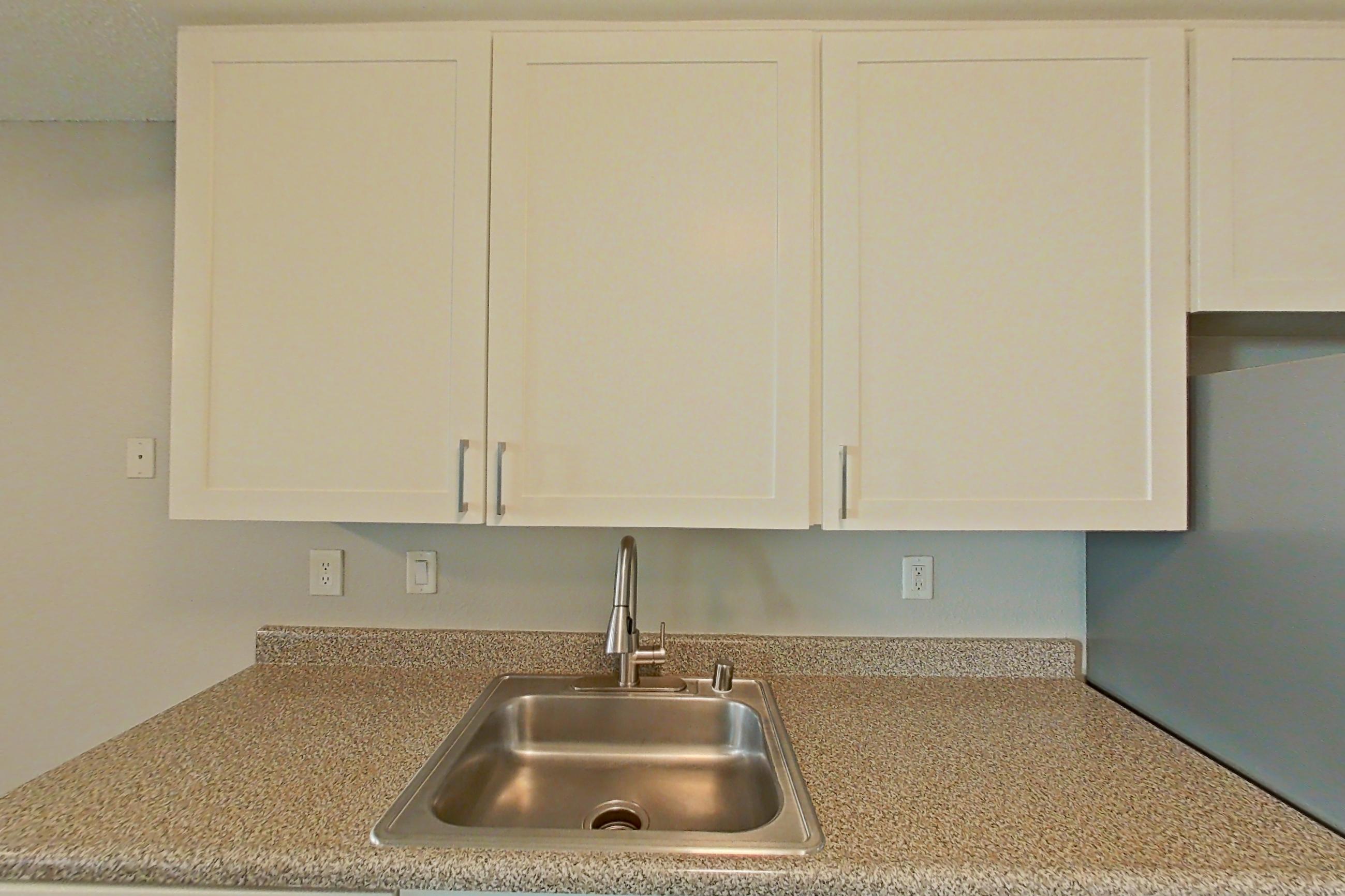 Kitchen with dishwasher, light stone countertops, light wood-finish flooring, refrigerator, and stainless steel appliances, Apartment 01-02 at Avana Rancho Cucamonga